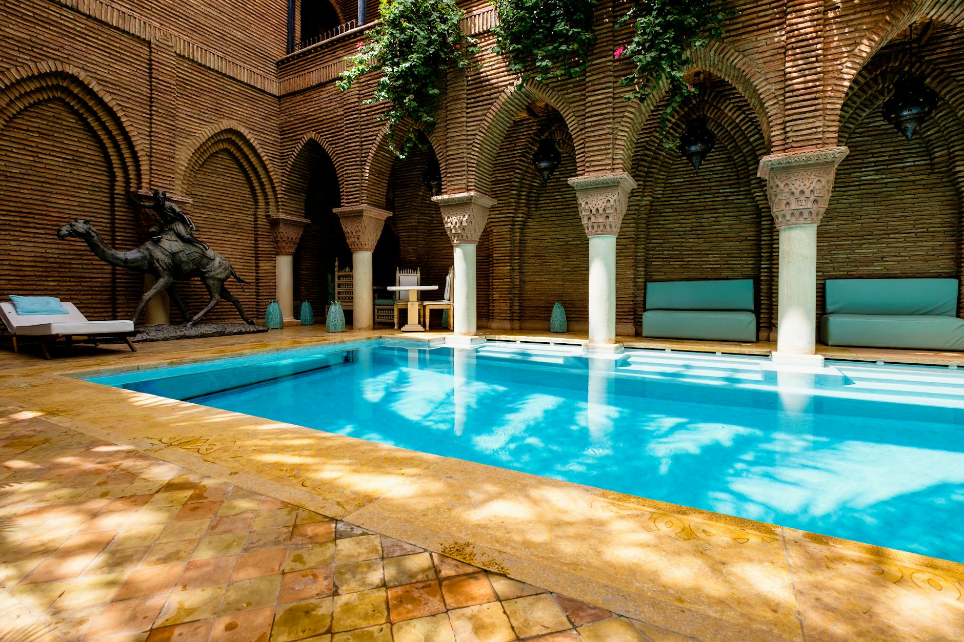 Marrakech hotel courtyard pool surrounded by arches and greenery