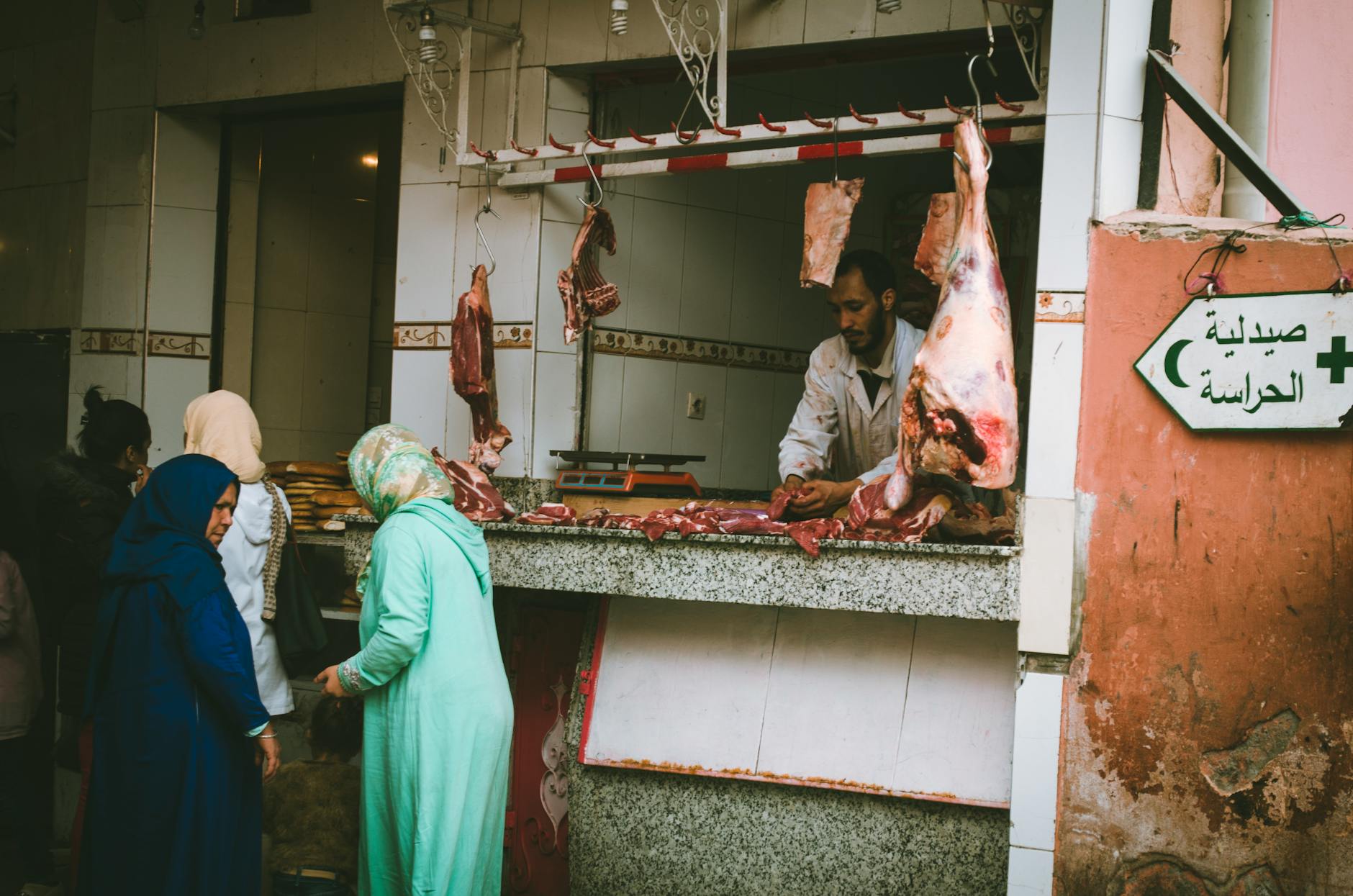 Outdoor market scene with a butcher serving customers