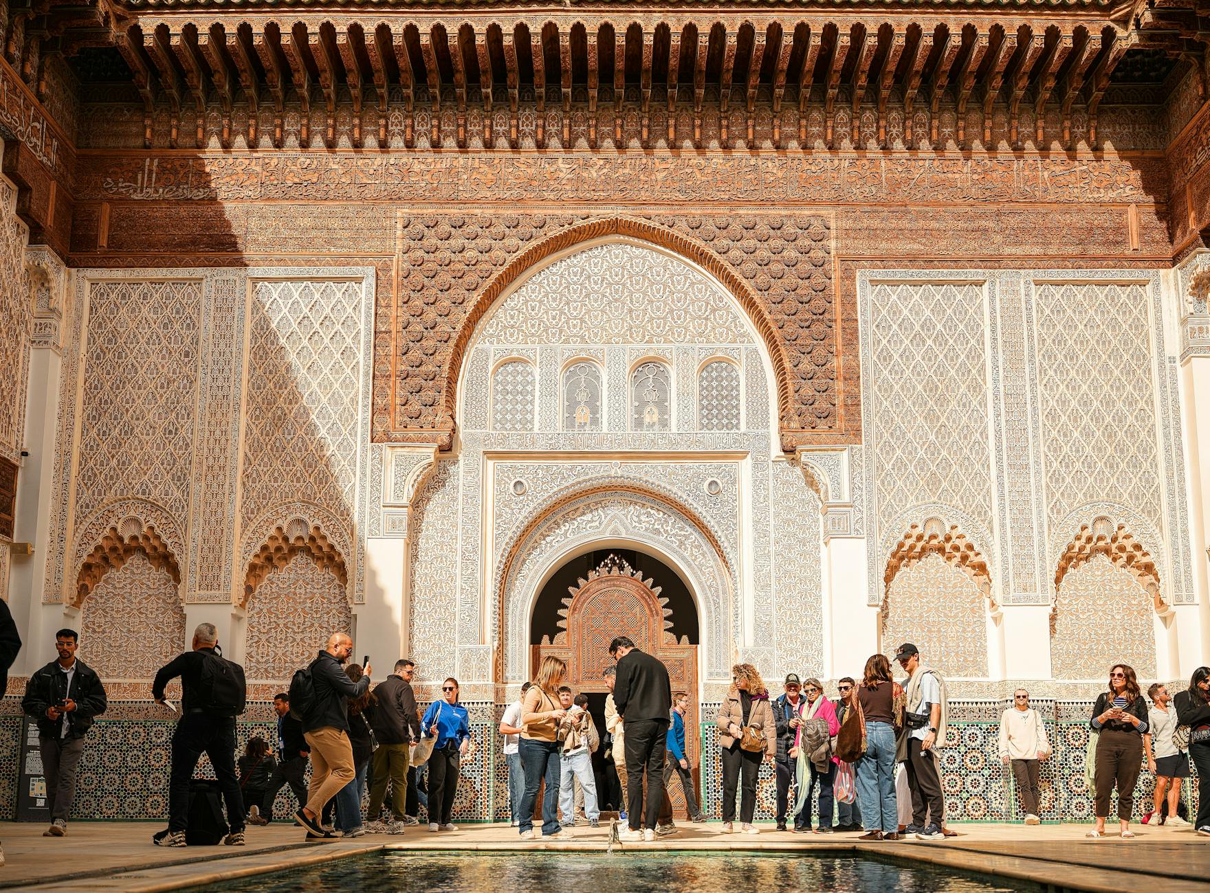 Visitors exploring the intricate architecture of Ben Youssef Madrasa in Marrakech