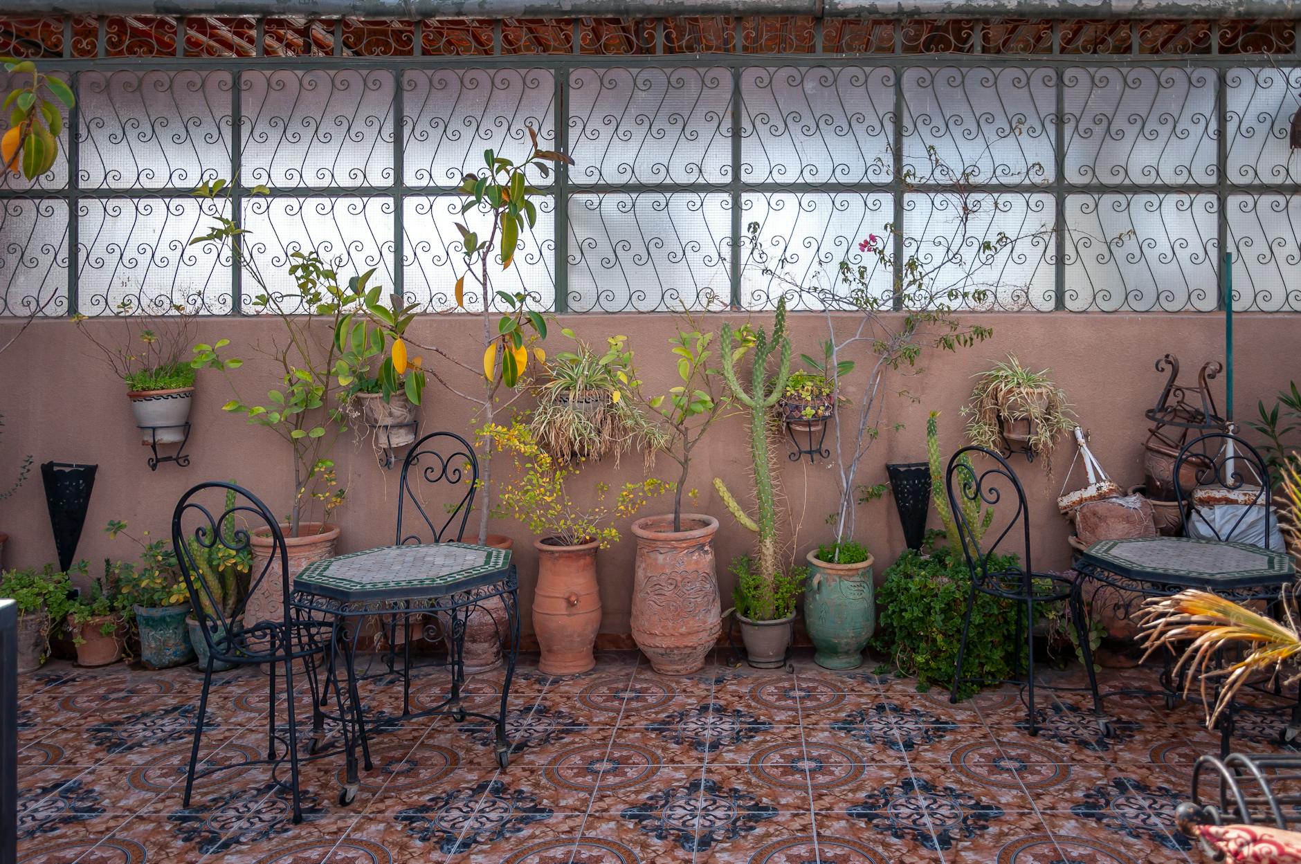 Moroccan cafe interior with mosaic floor, plants, and small tables