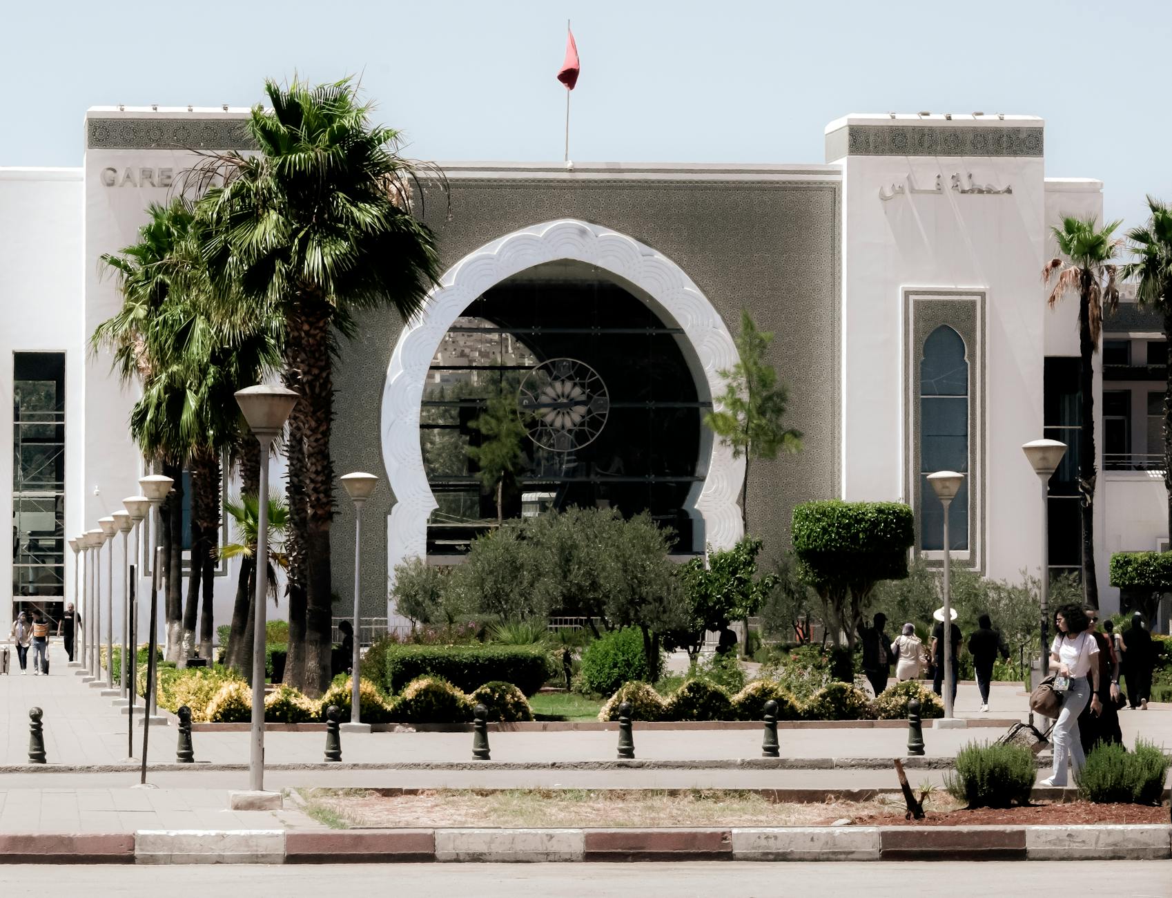 Ornamented Moroccan train station entrance with palm trees