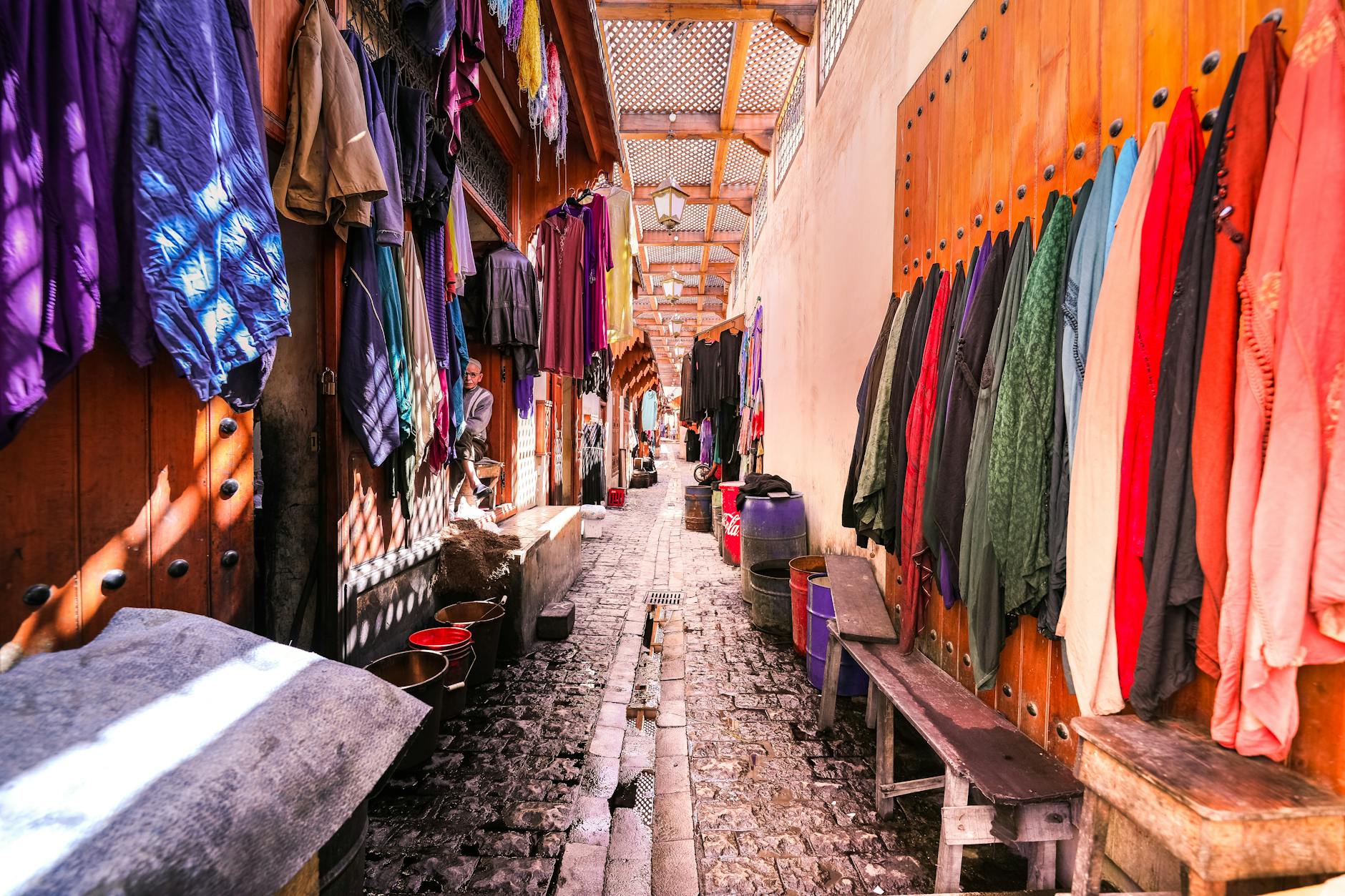 Colorful fabrics hanging in a sunny Marrakech market alley