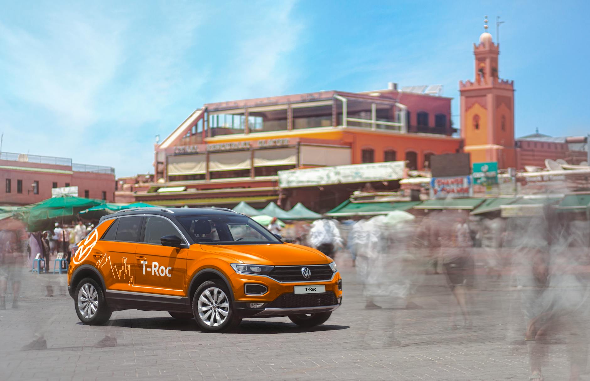 Orange SUV moving through a busy Marrakech market street