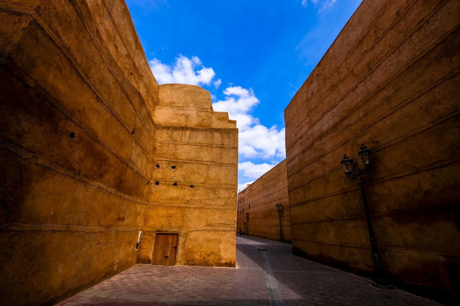 Historic Marrakech wall and street lamp under a blue sky