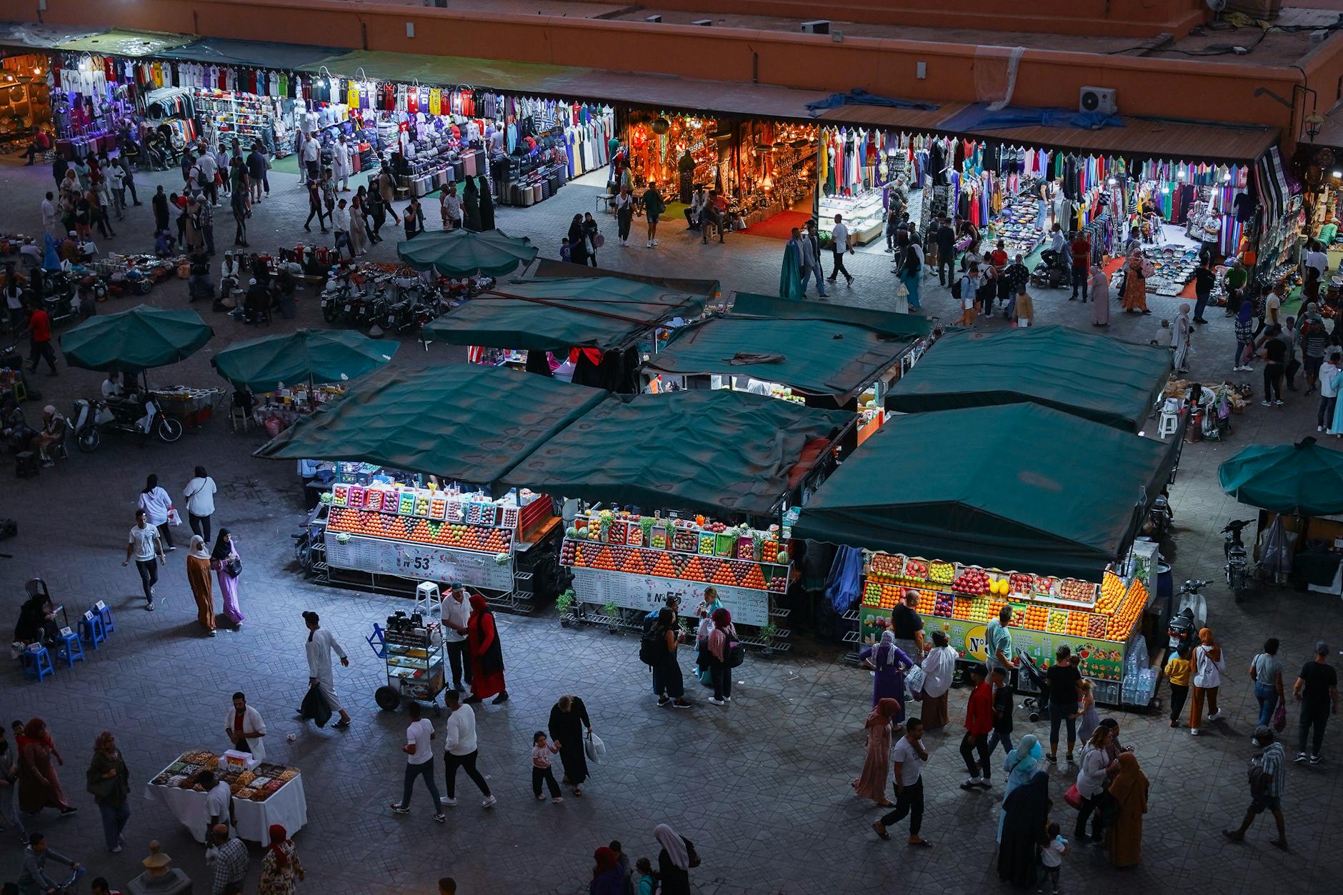 Overhead view of a crowded Marrakech night market with colorful stalls