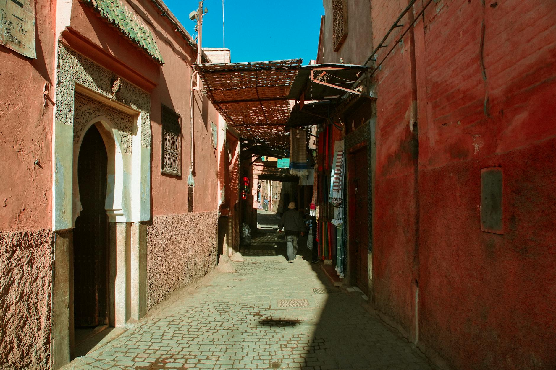 Narrow Moroccan alleyway with red walls and cobblestones