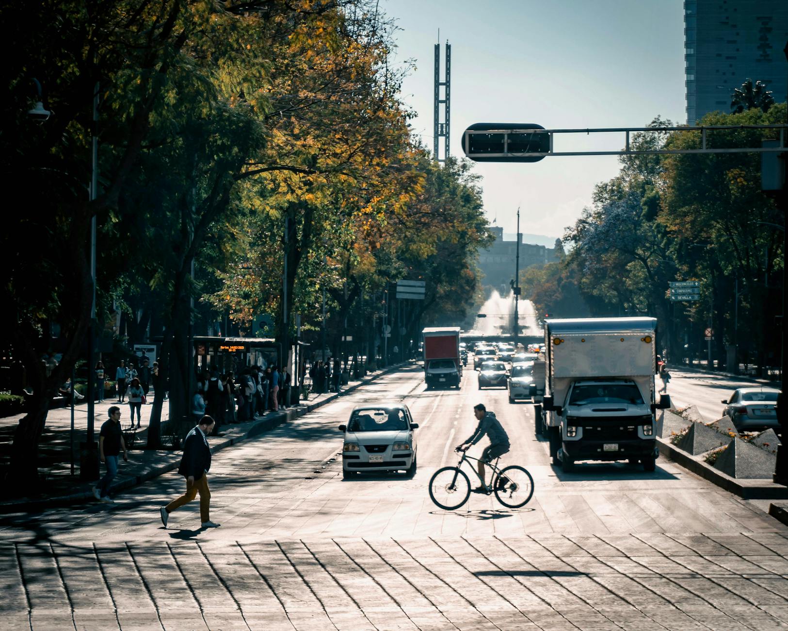 Pedestrians and a cyclist crossing a busy Mexico City street