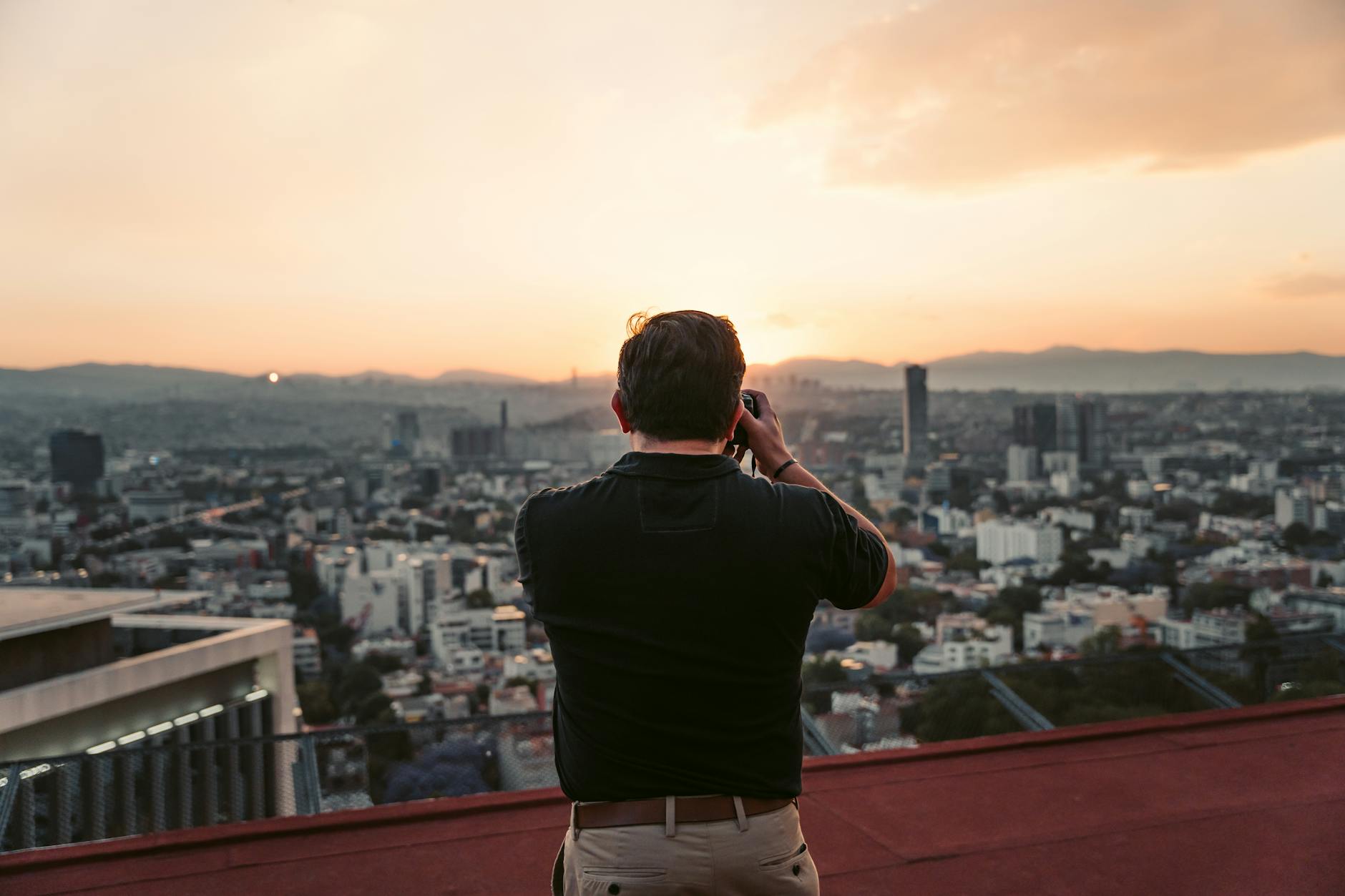 Photographer capturing the Mexico City skyline from a rooftop at sunset