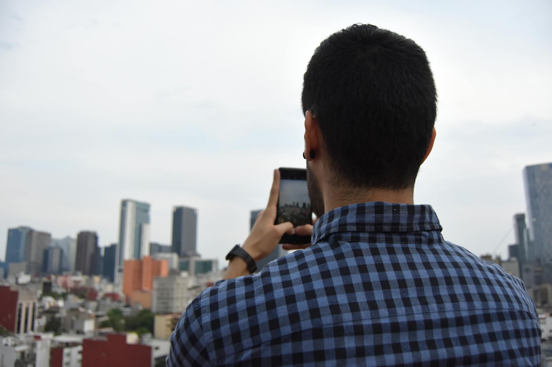 Man photographing the Mexico City skyline with a smartphone