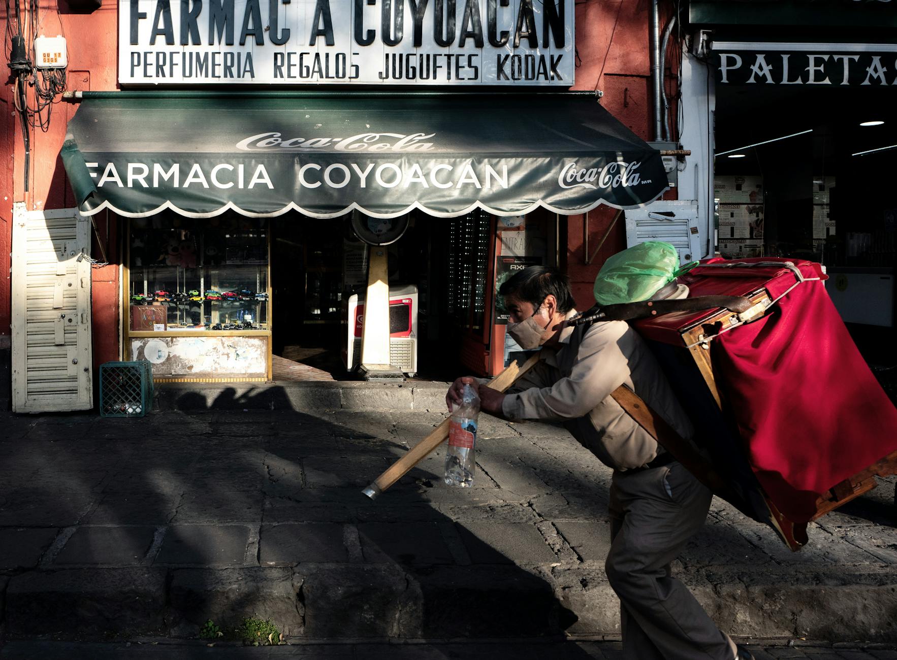 Pedestrian passing a pharmacy storefront in Coyoacan, Mexico City