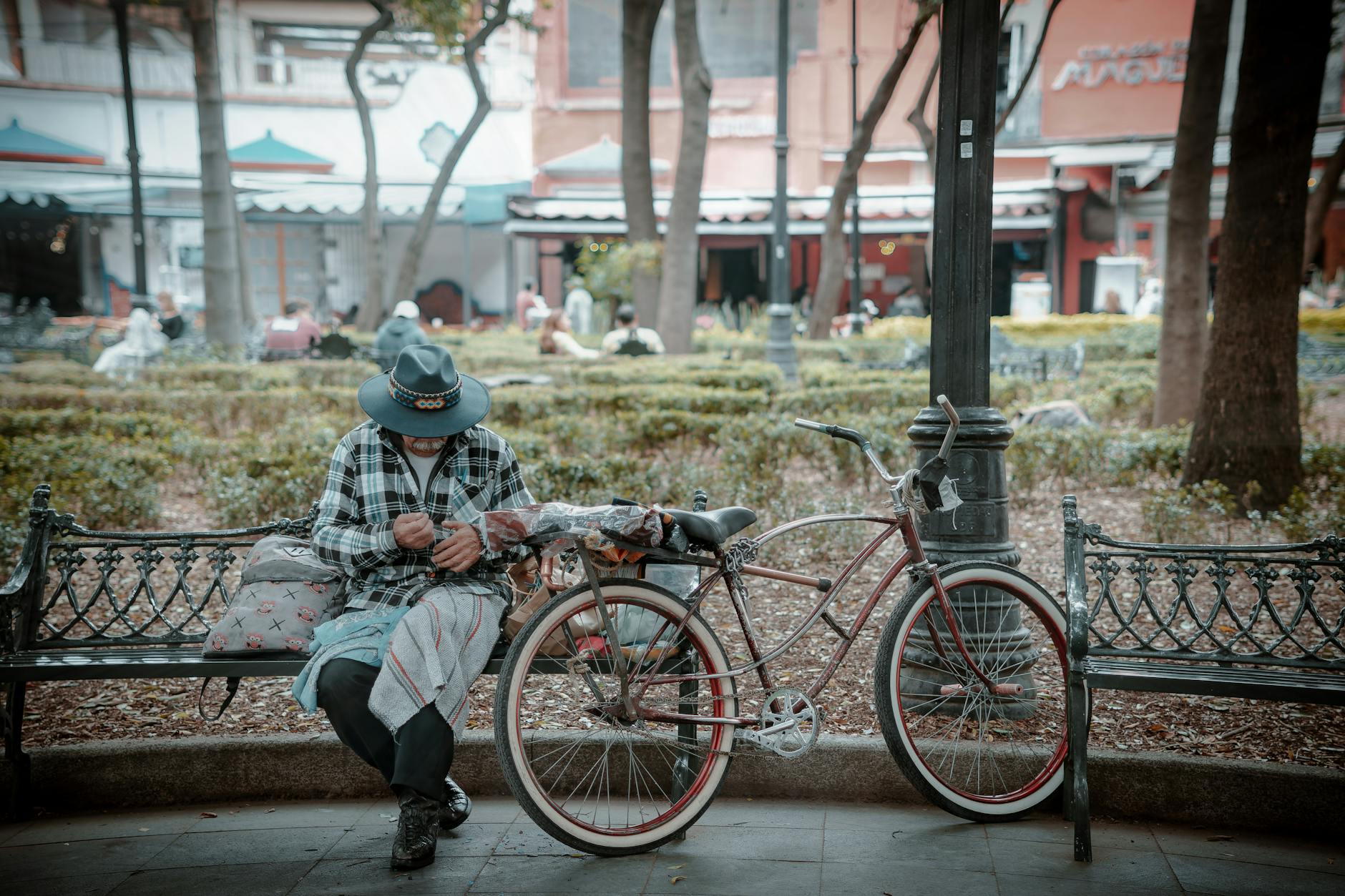 Man seated on a park bench with a bicycle in Mexico City
