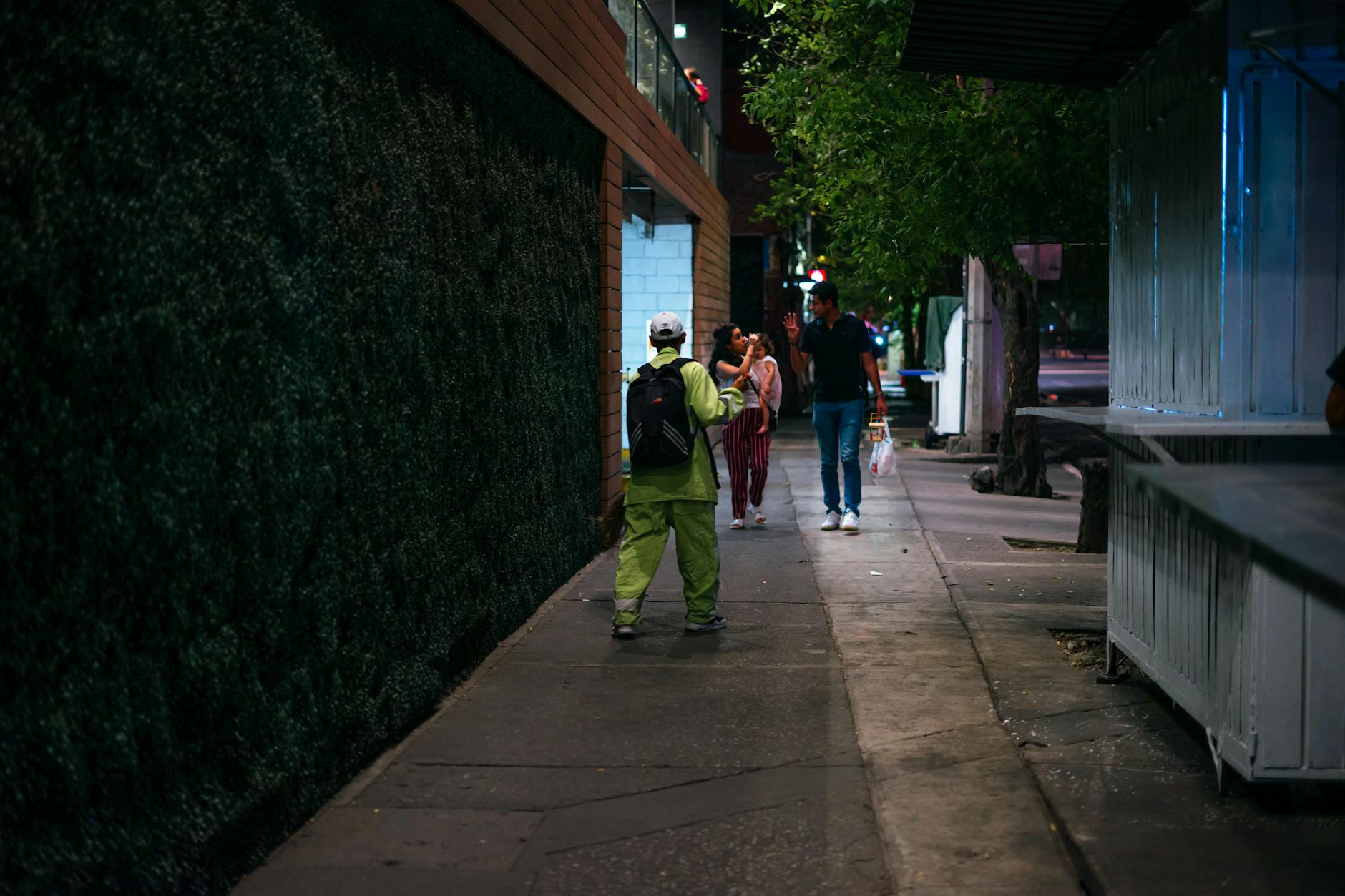 People walking along a Mexico City sidewalk at night