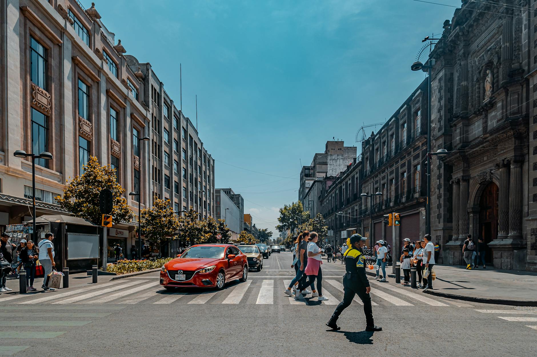 Pedestrians and a police officer crossing a busy Mexico City street