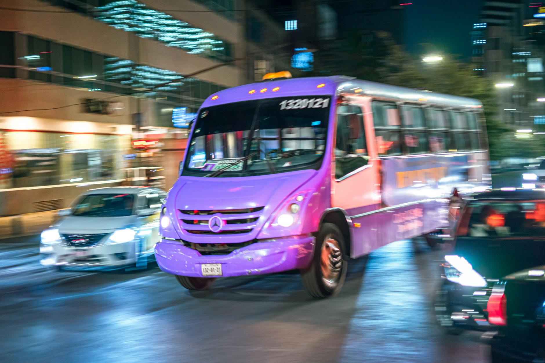 Red bus moving through Mexico City traffic at night