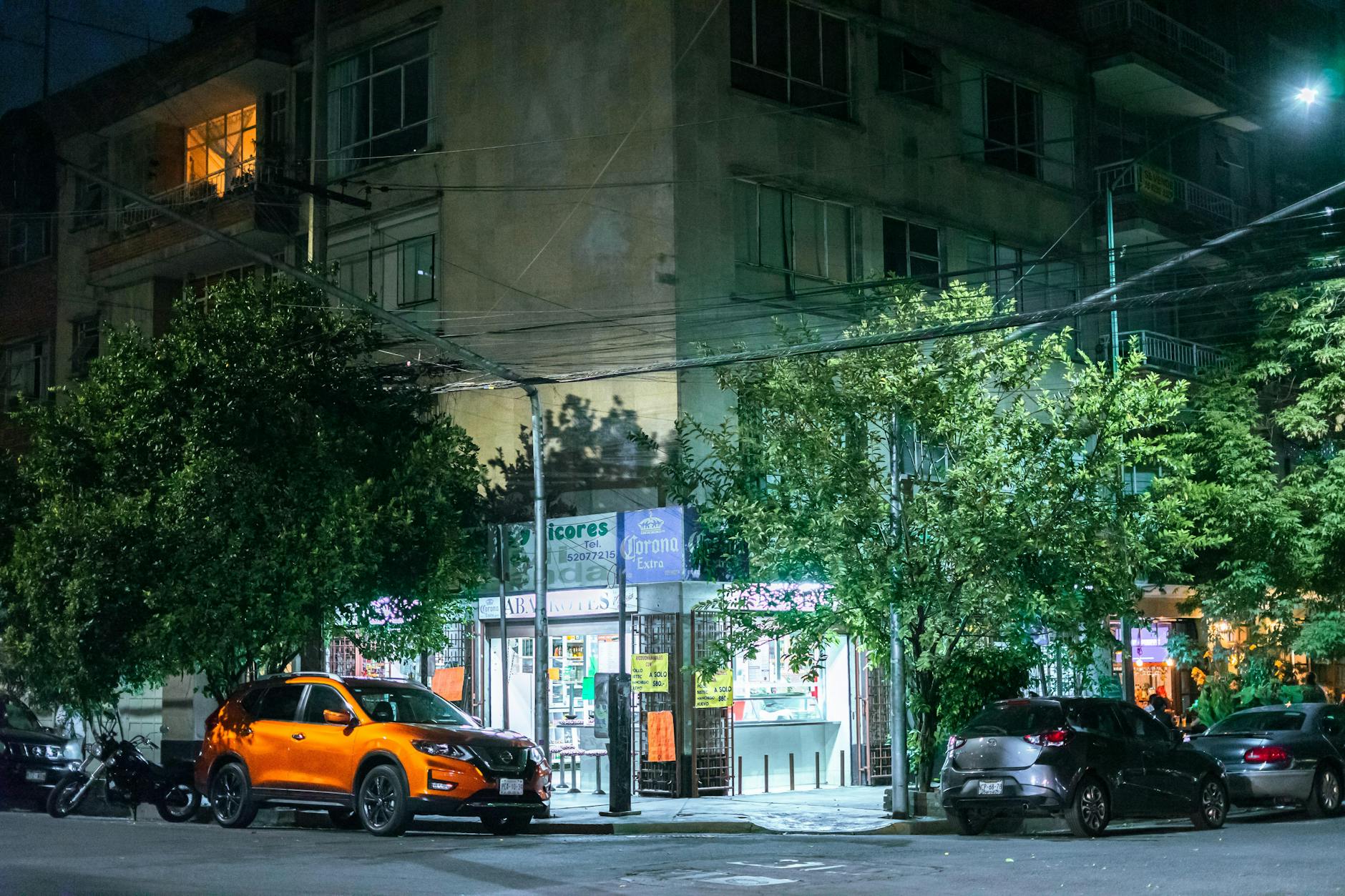 Night street with local shops and parked cars in Mexico City