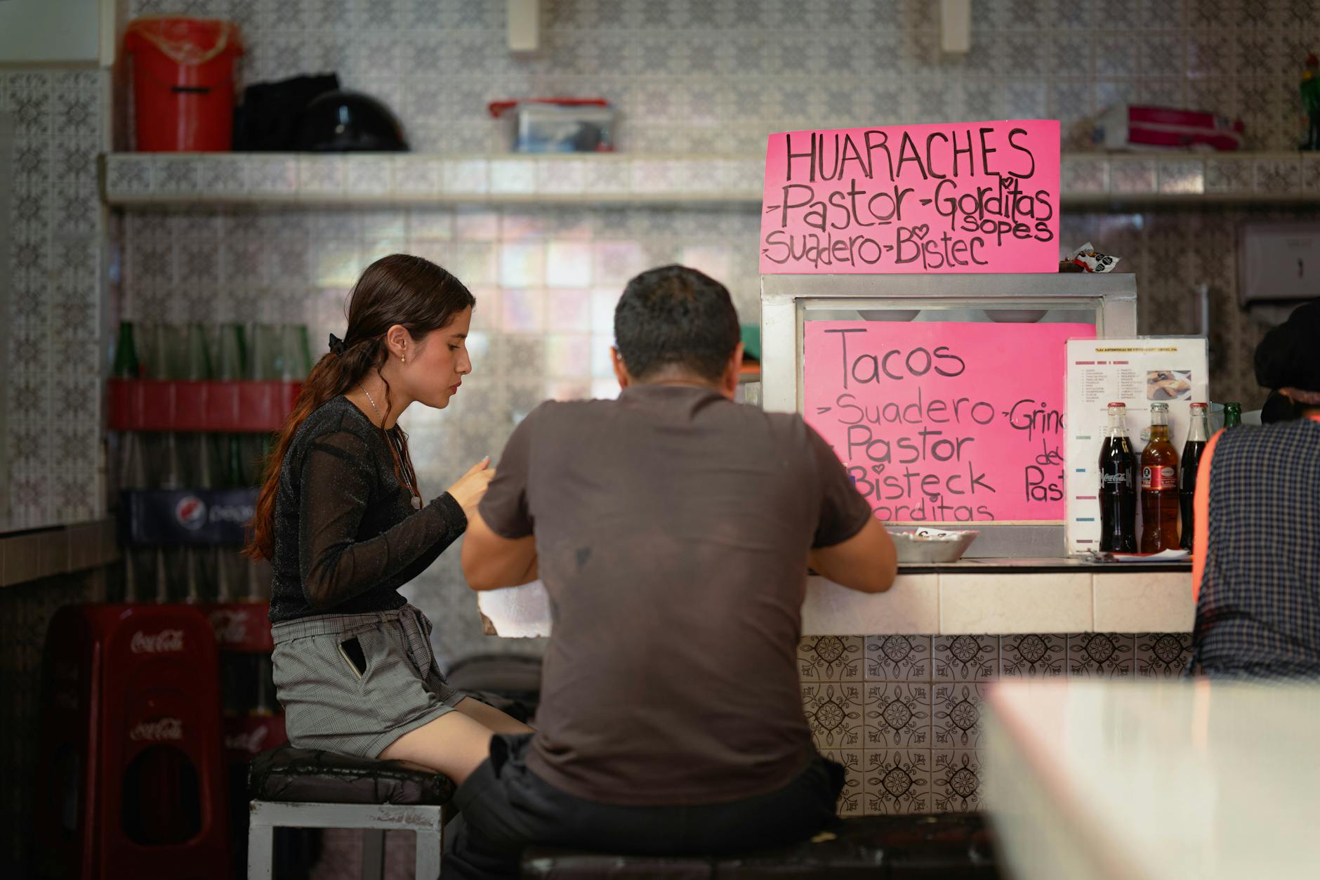 Two people seated at a Mexico City street food counter