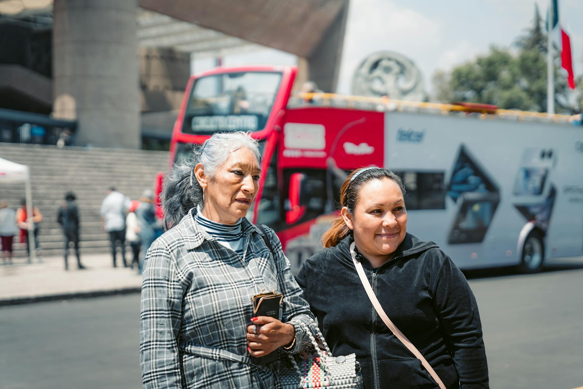Women standing near a tour bus on a busy Mexico City street