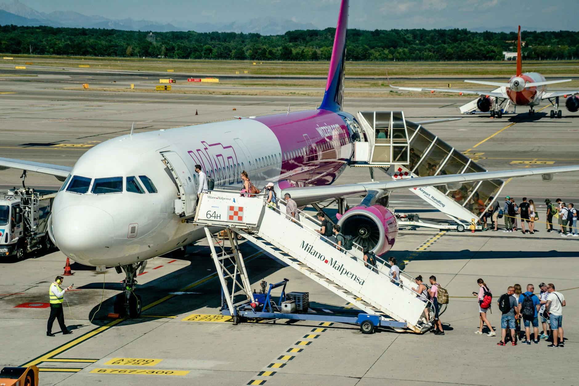 Travelers boarding an airplane at Milan Malpensa Airport
