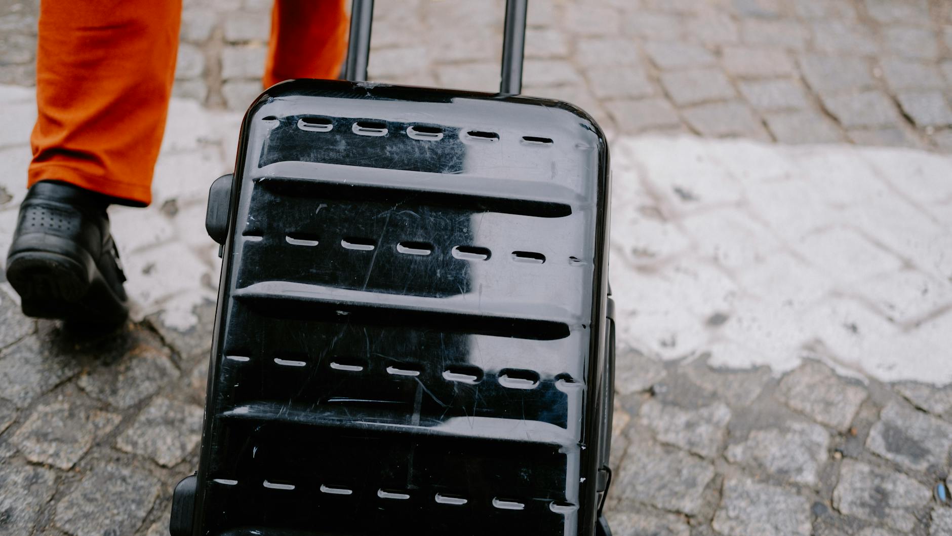 Person pulling a trolley bag on a street