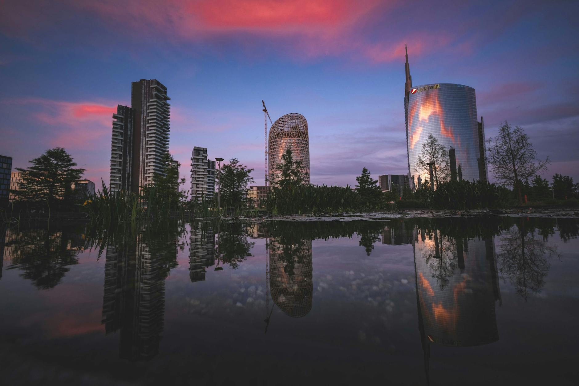 Milan skyline reflected in water at sunset