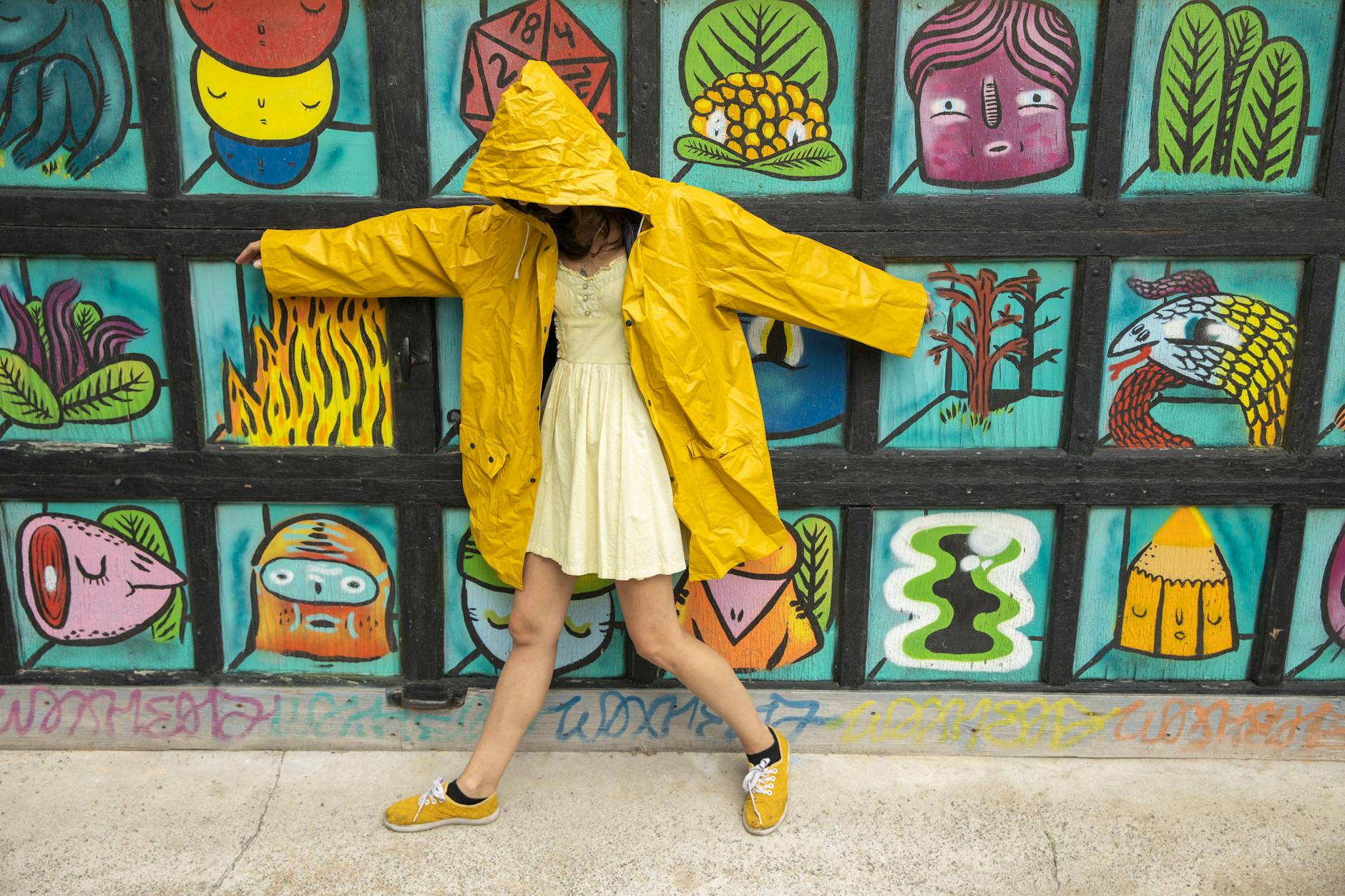 Woman in yellow raincoat posing by a Montreal mural