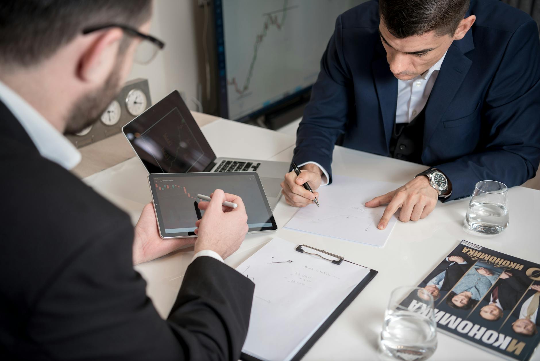 Businessmen analyzing market trends on digital devices