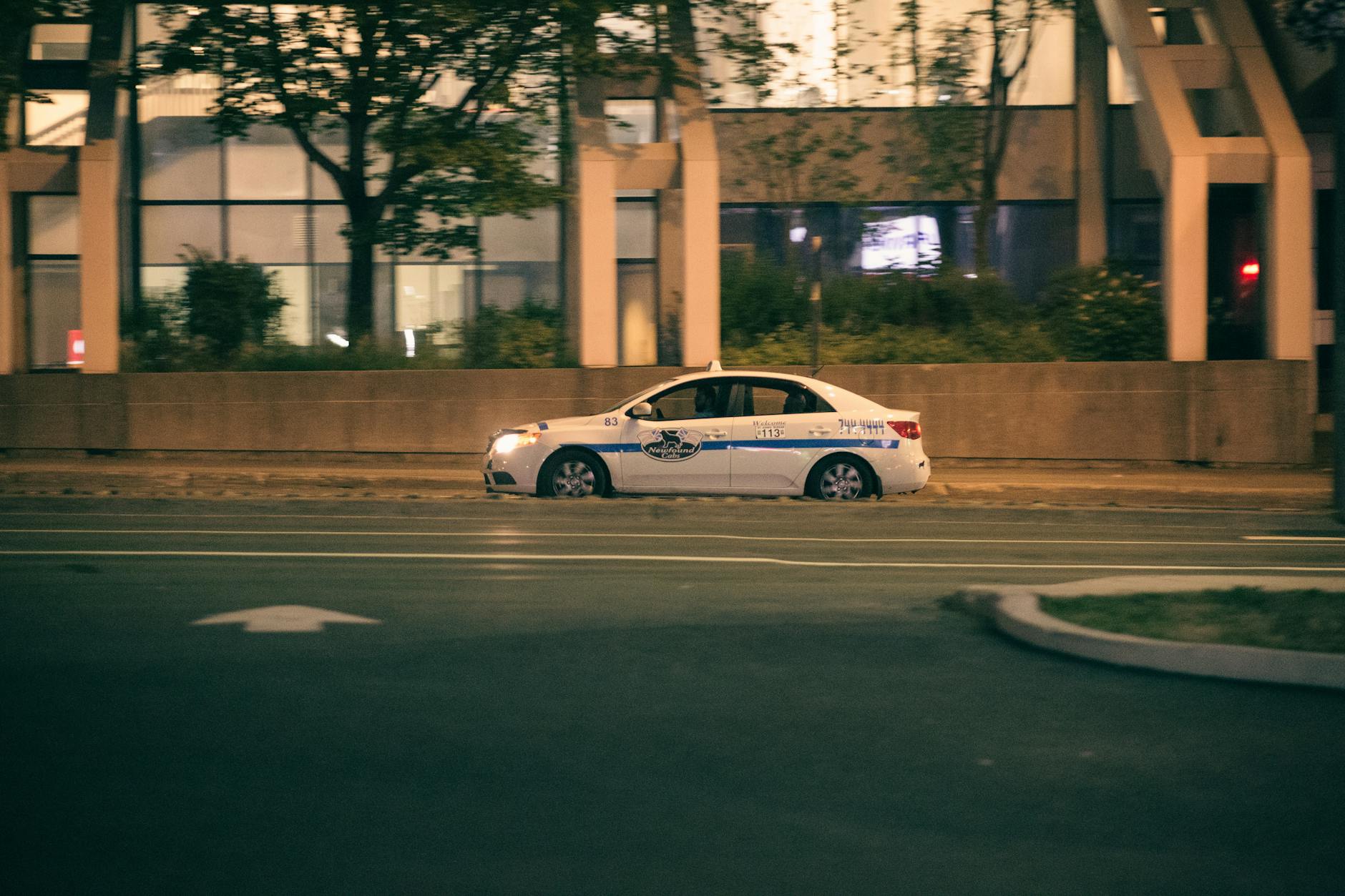 White taxi parked on a city street at night