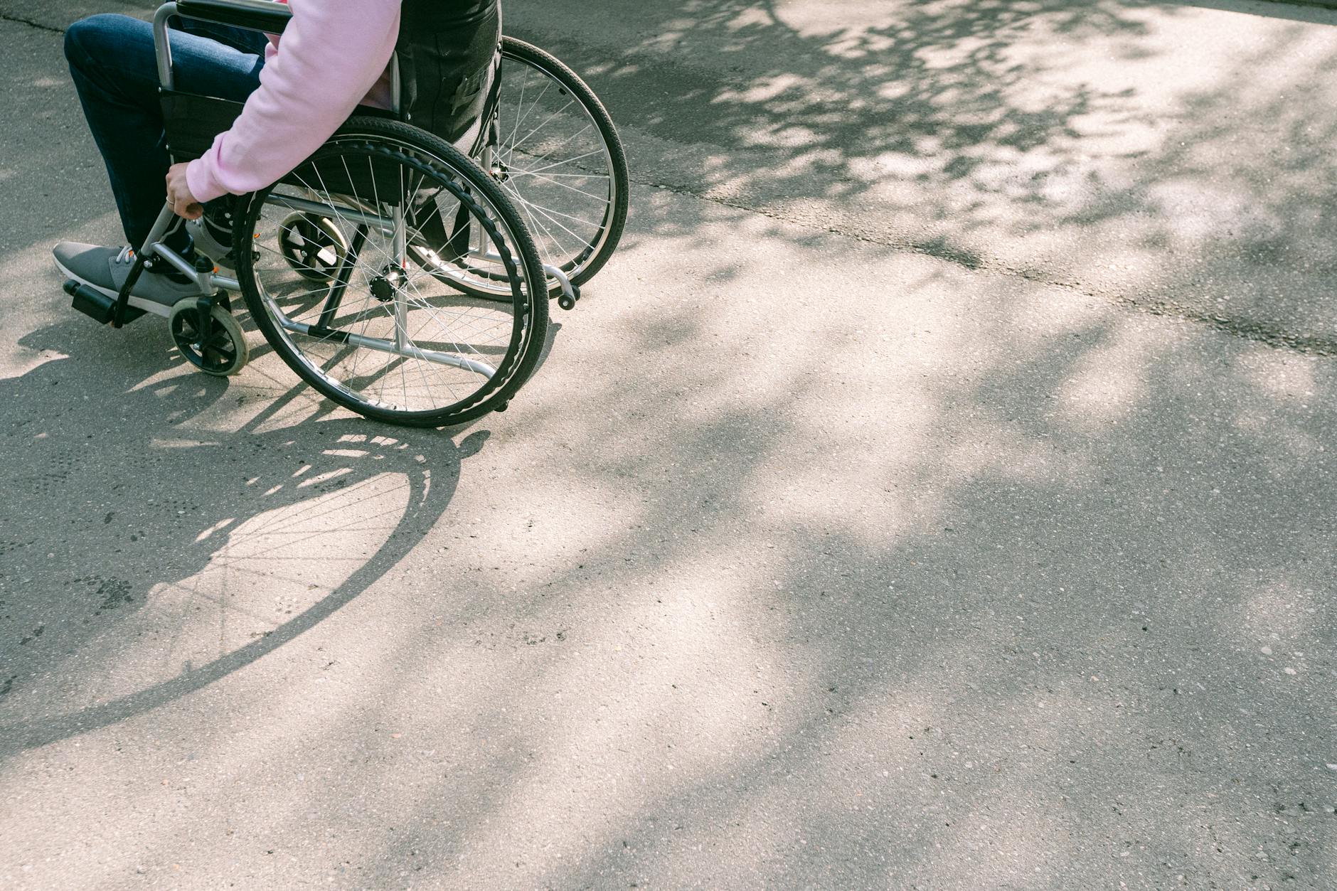 Person using a wheelchair on a sunlit road