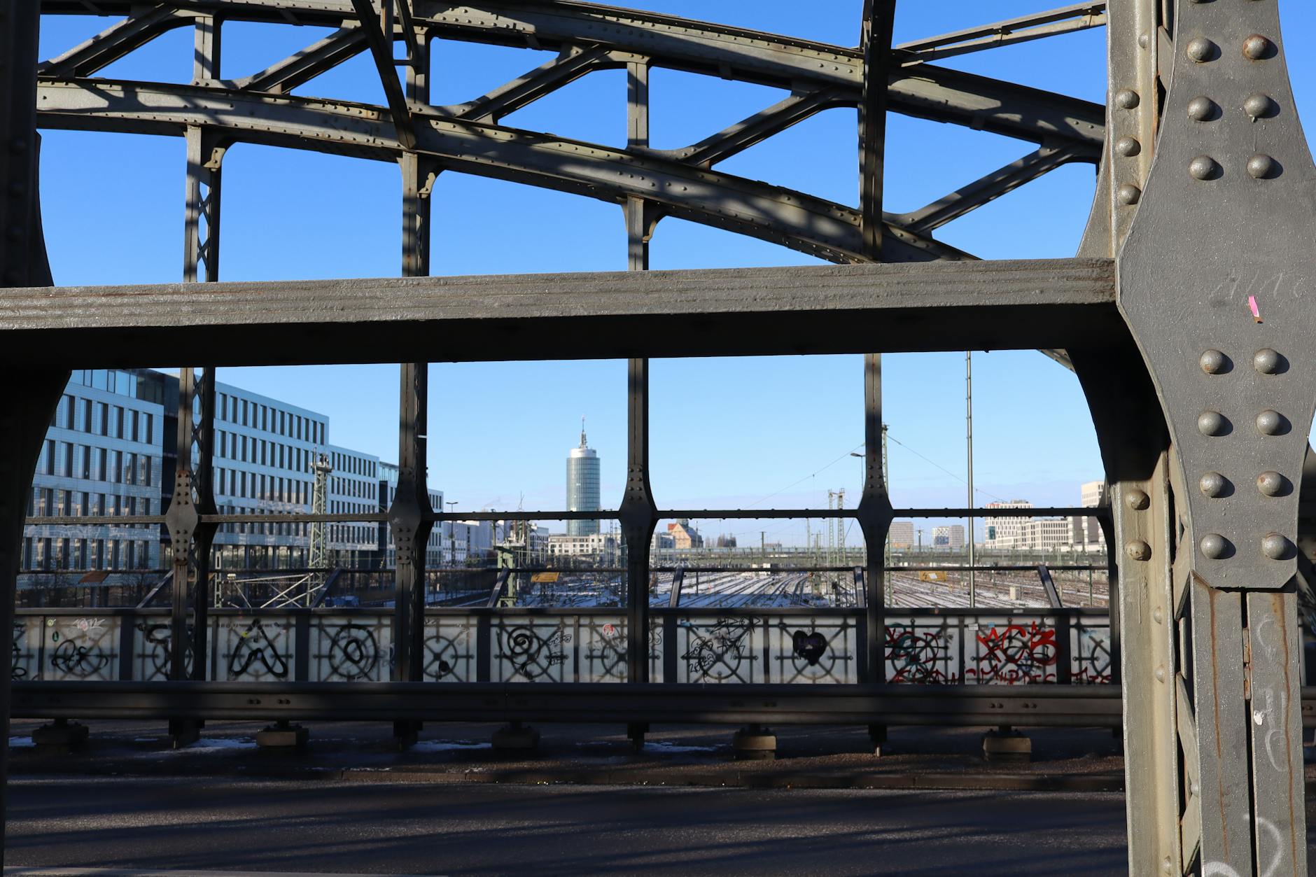 Metal bridge framing a Munich skyline