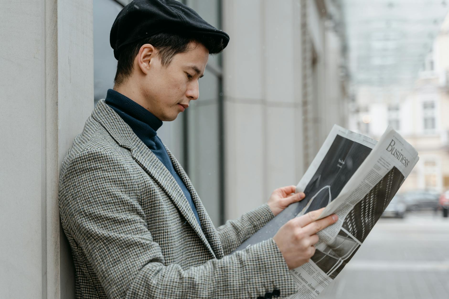 Person reading a newspaper outdoors in an urban setting