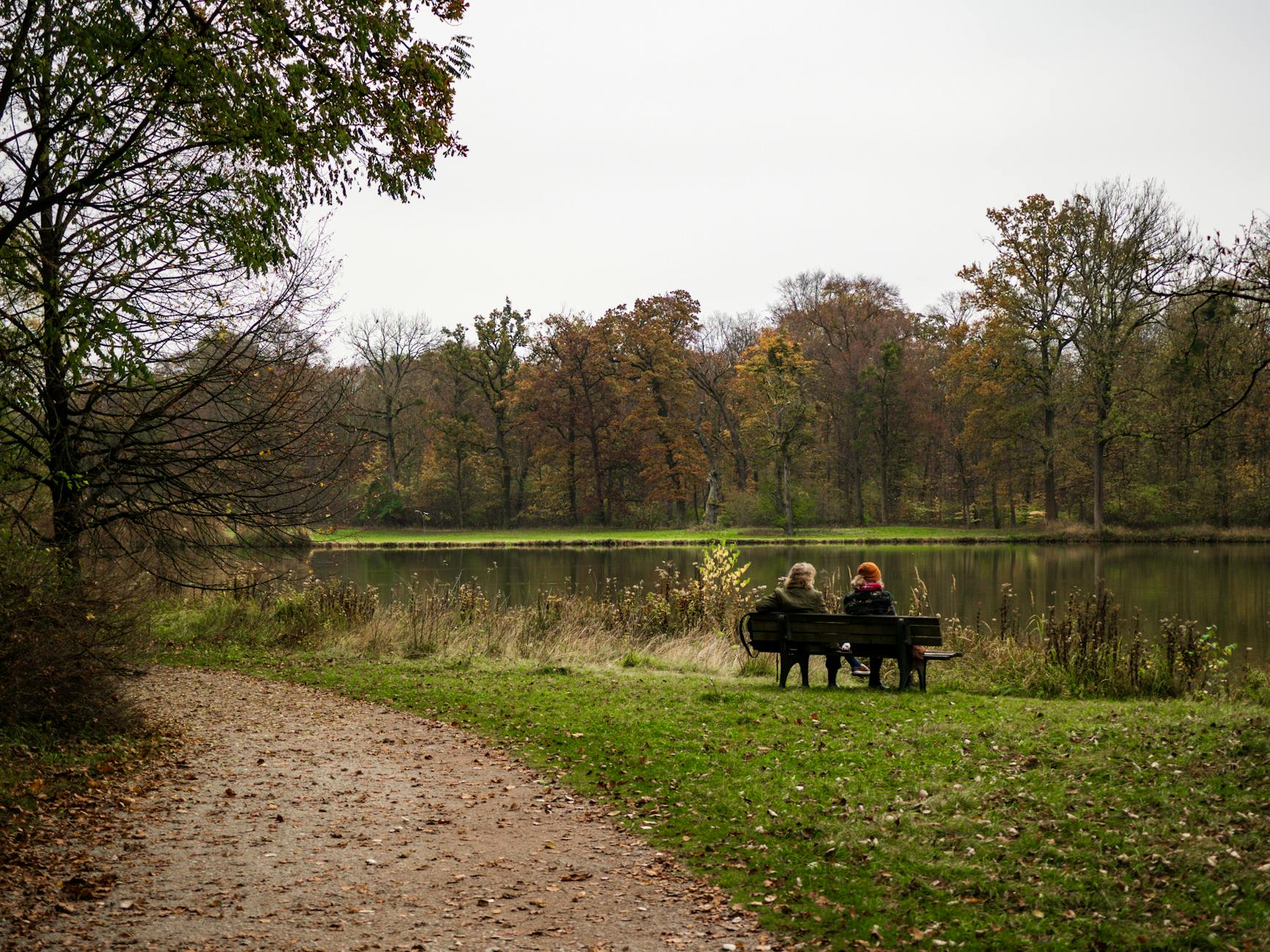 People sitting on a park bench by a Munich lake