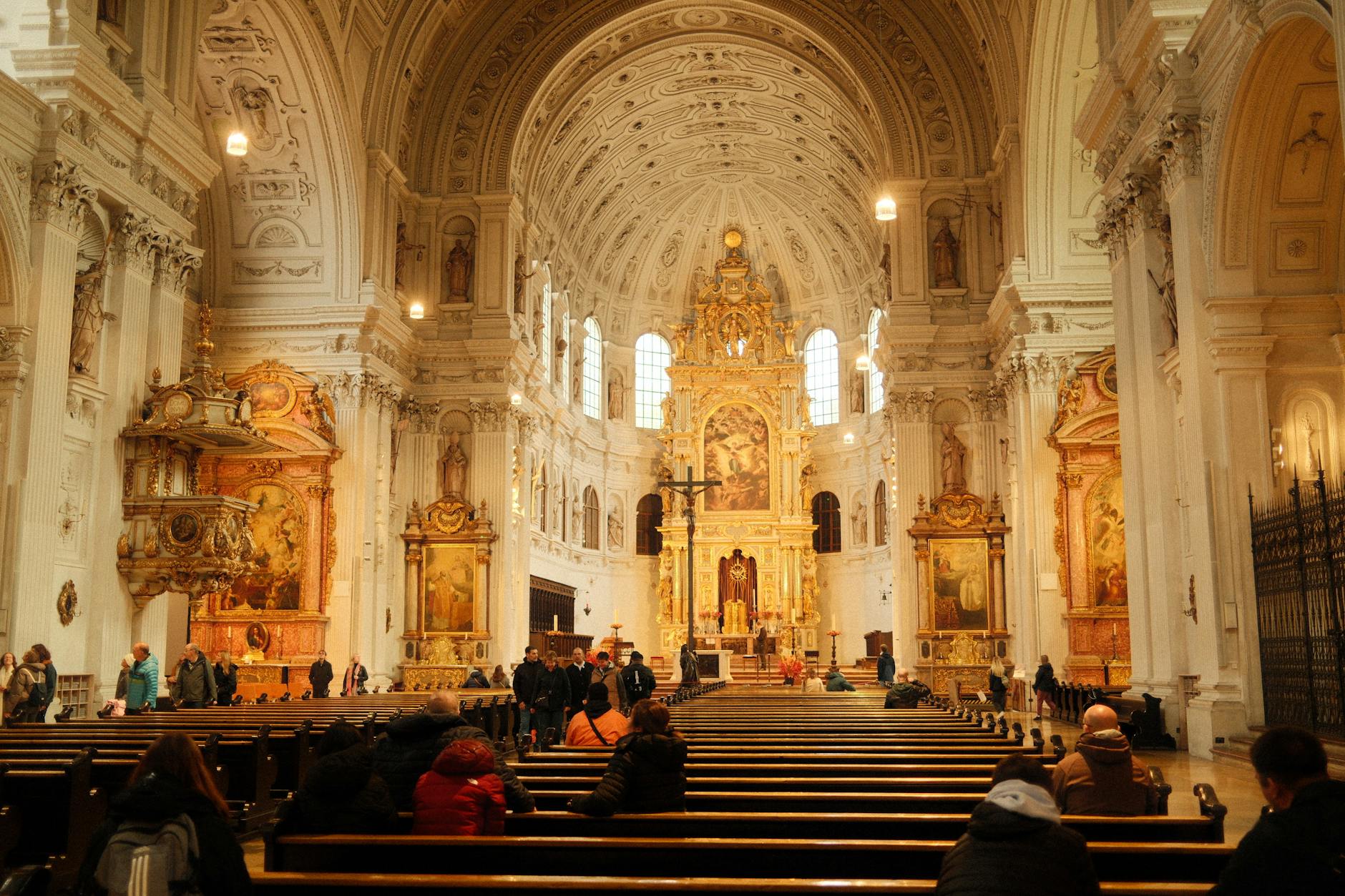 Visitors inside an ornate Baroque cathedral interior