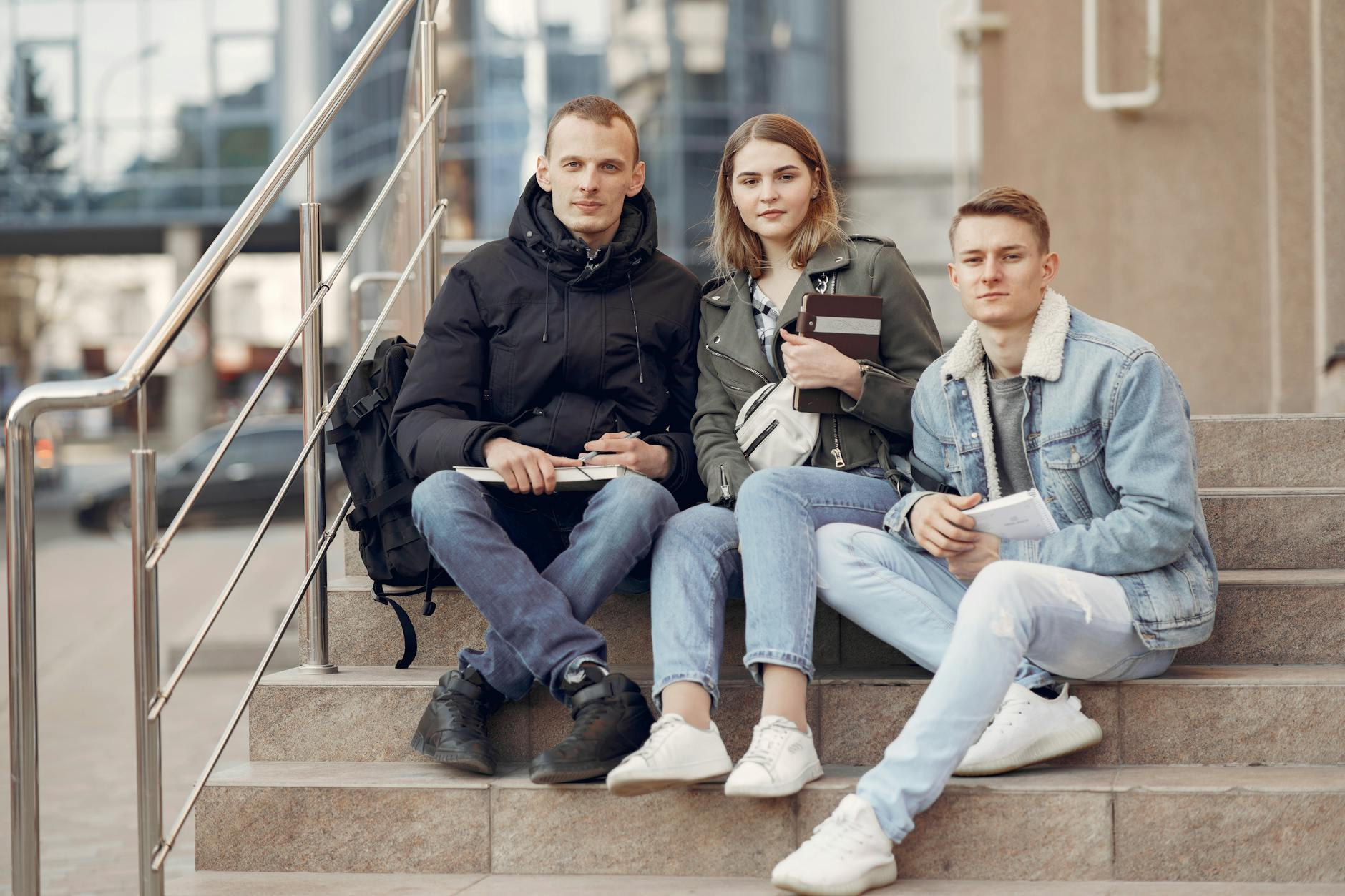 Students sitting together with books near a modern building