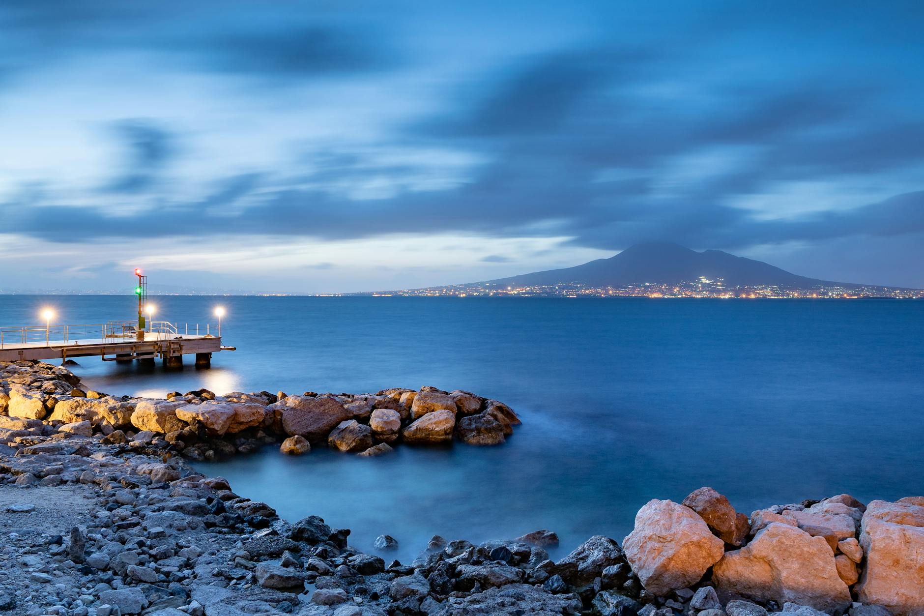 Rocky shoreline near Naples with Mount Vesuvius at twilight