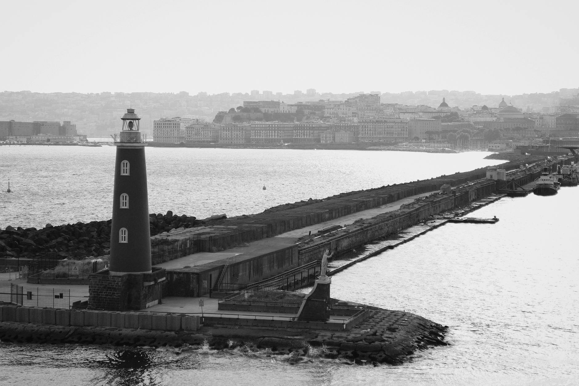 Black and white harbor view with lighthouse and distant city