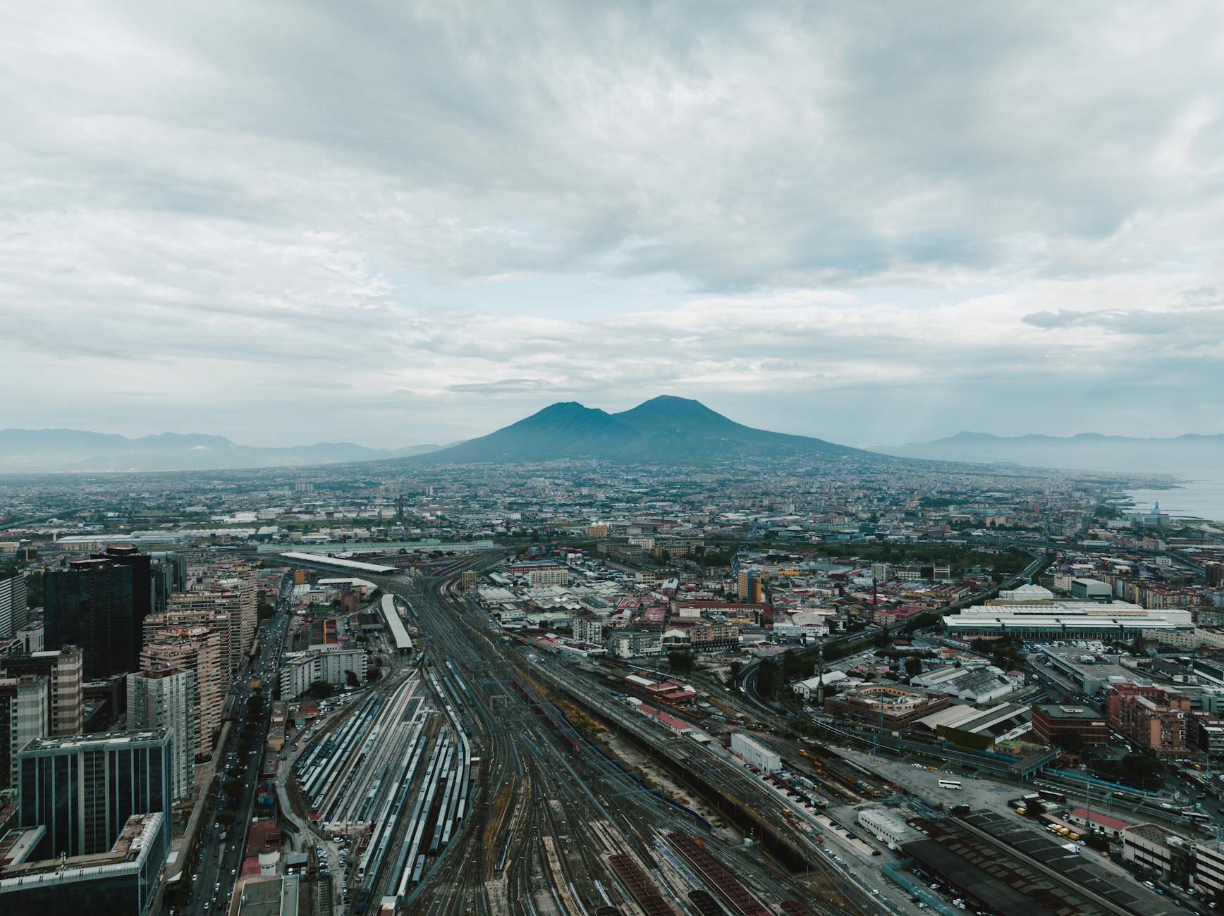 Aerial cityscape of Naples with Mount Vesuvius under clouds