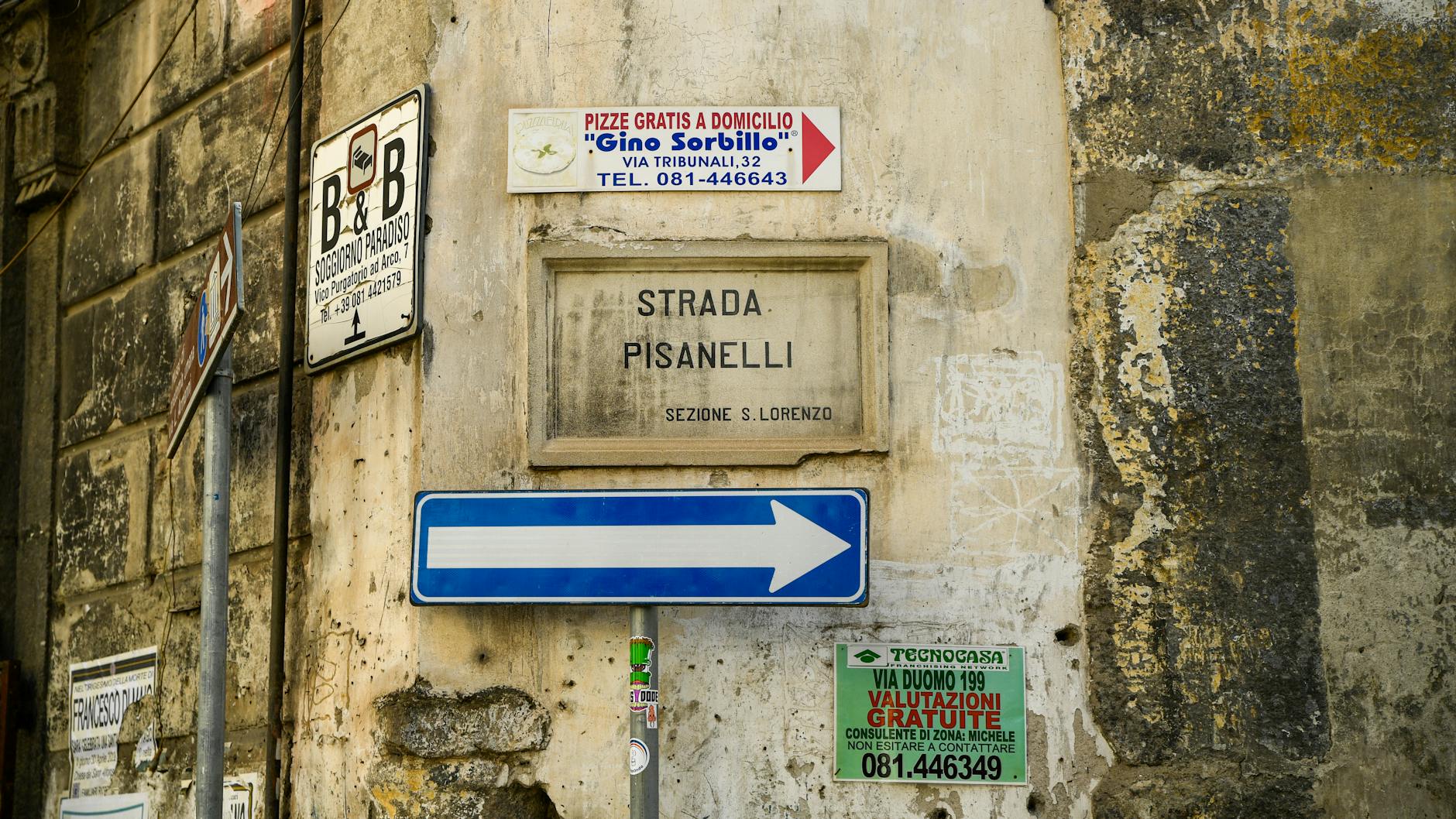 Historic street signs on a rustic building wall in Naples