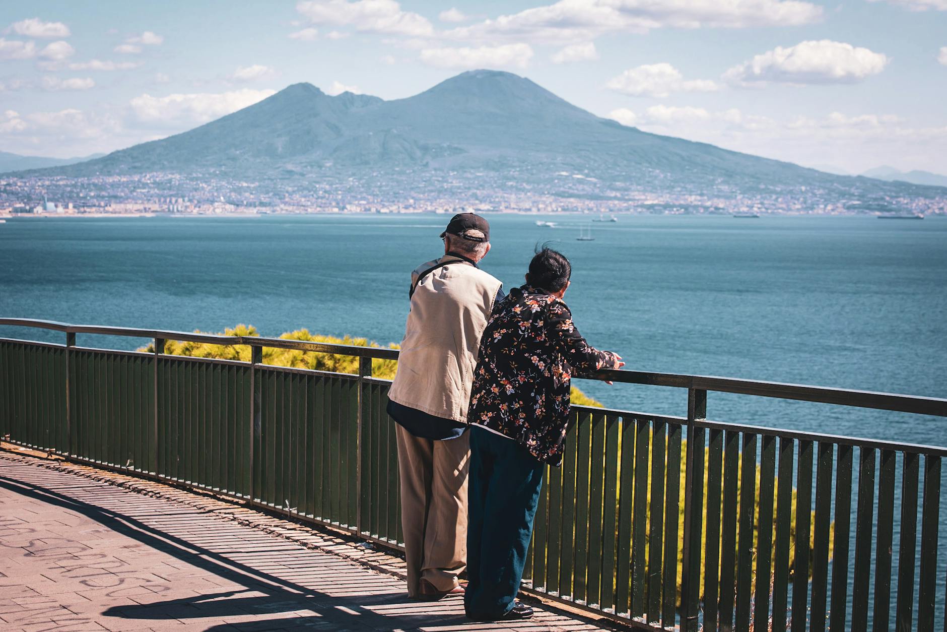 Older couple by a railing looking toward Mount Vesuvius from Naples