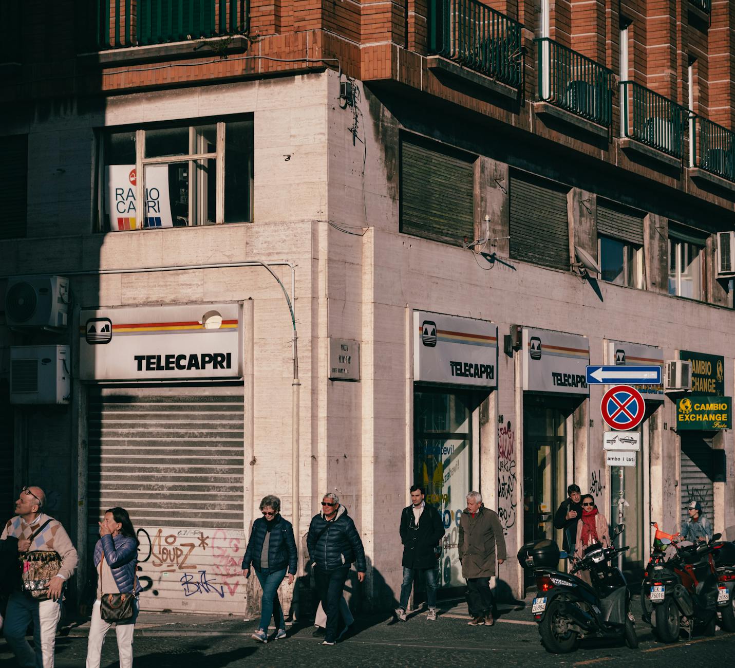 Sunlit street corner in Naples with pedestrians
