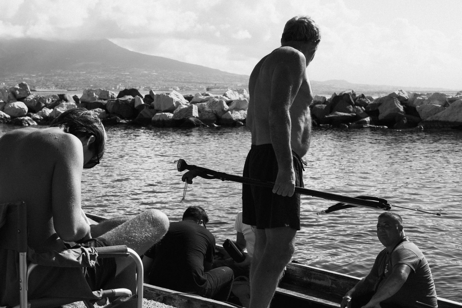 People by the sea in Naples with Mount Vesuvius behind them