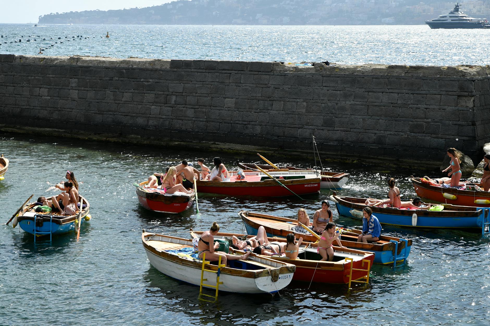 People relaxing in colorful boats at Naples harbor