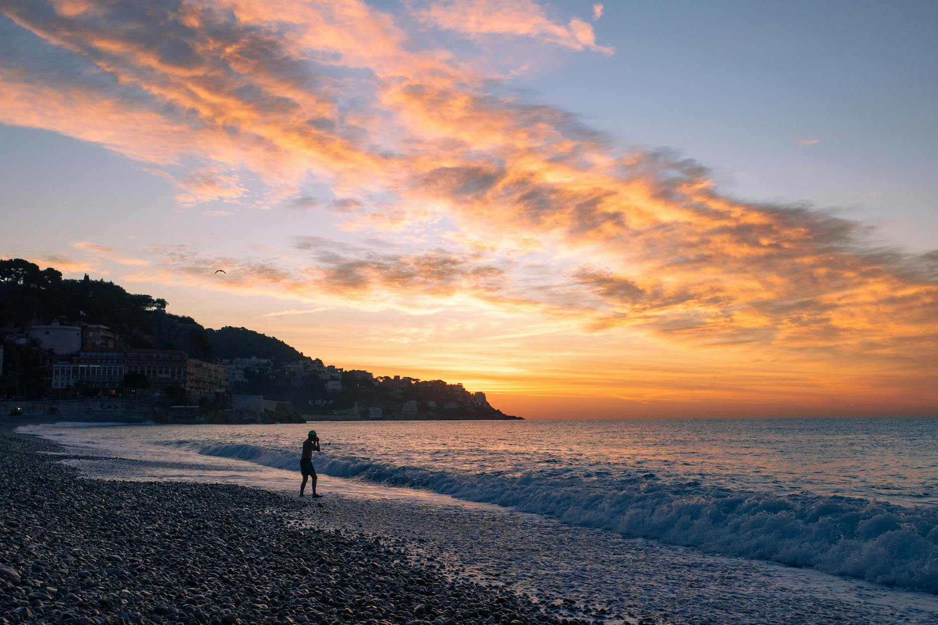 Sunset over the pebble beach in Nice with waves and vivid sky