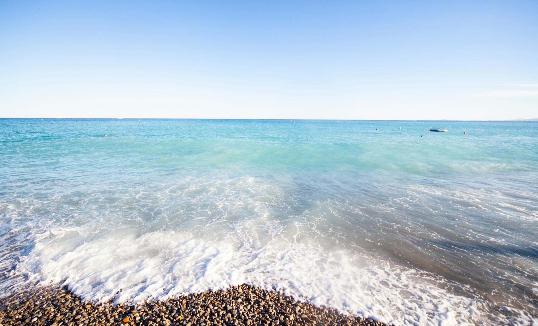 Pebble shoreline and blue waves in Nice
