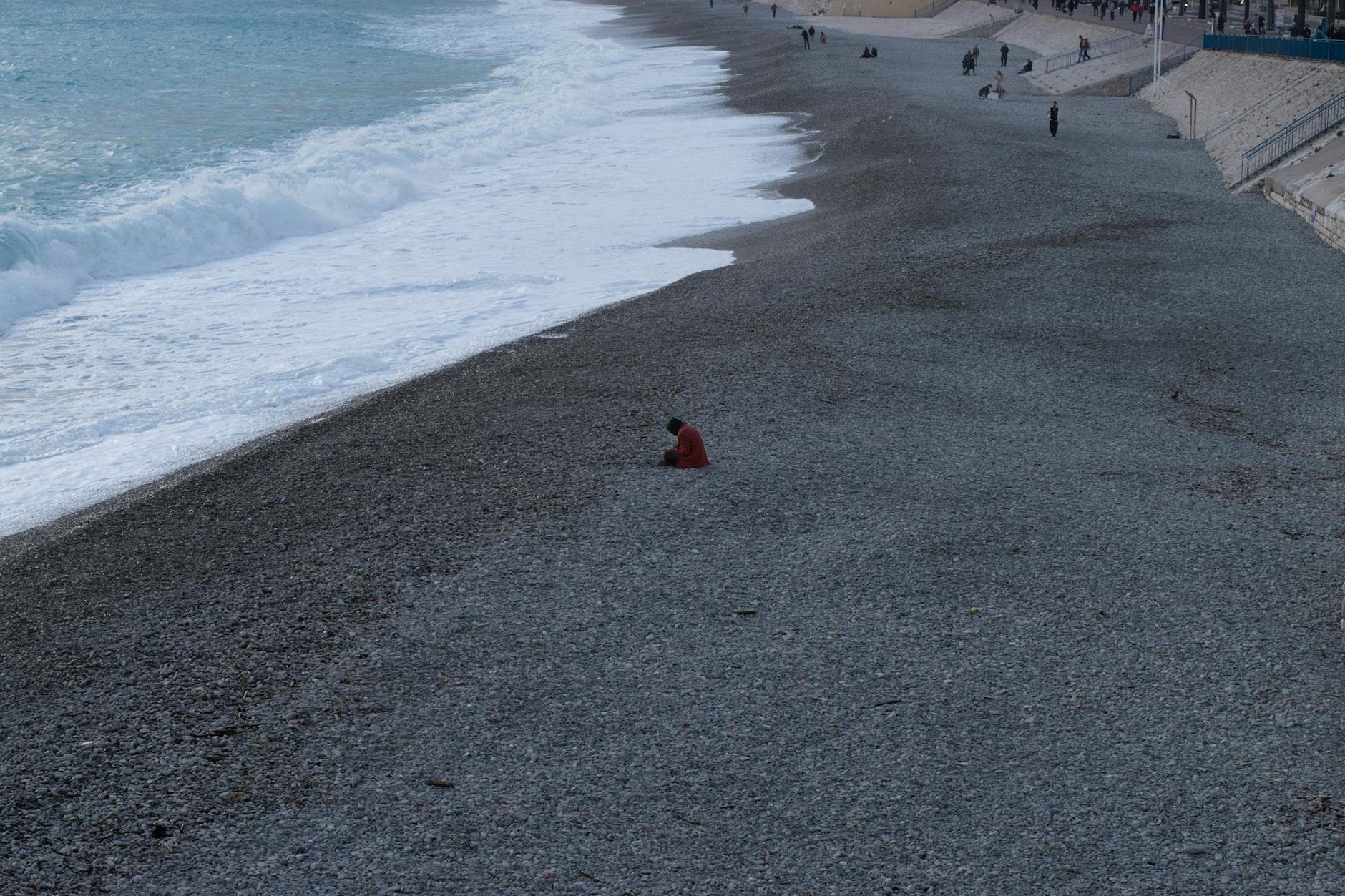 Person sitting on a pebbled beach in Nice