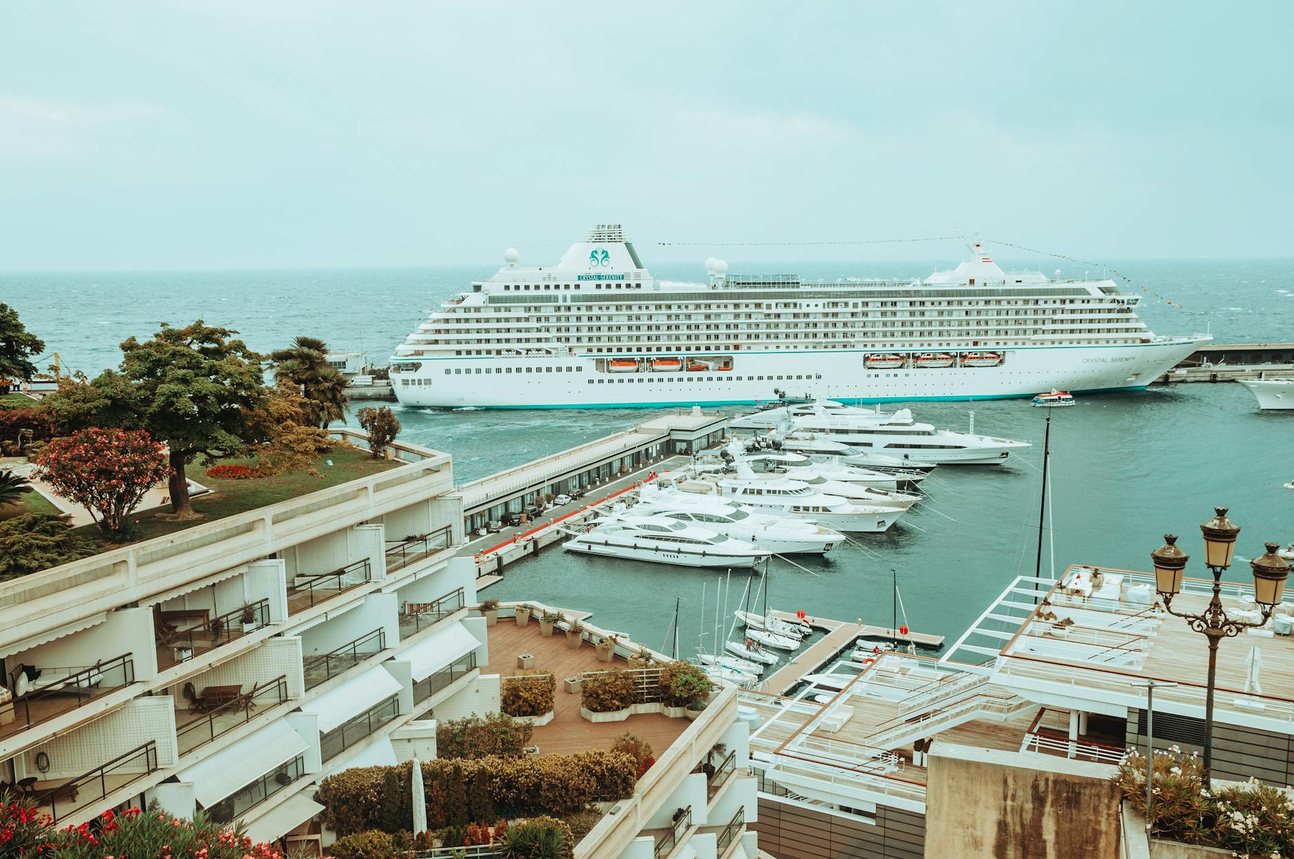 Cruise ship docked at Monaco harbor with yachts and cityscape