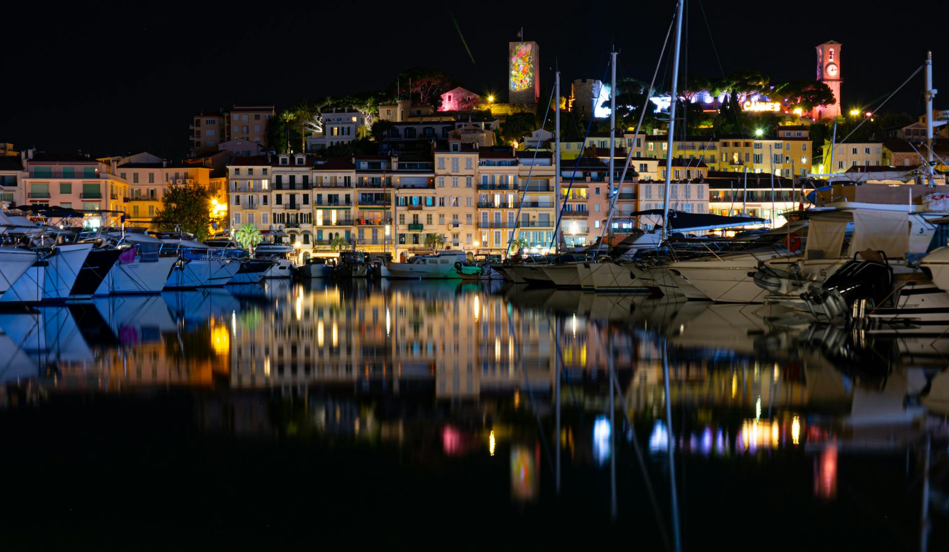 Cannes harbor at night with yachts and illuminated buildings