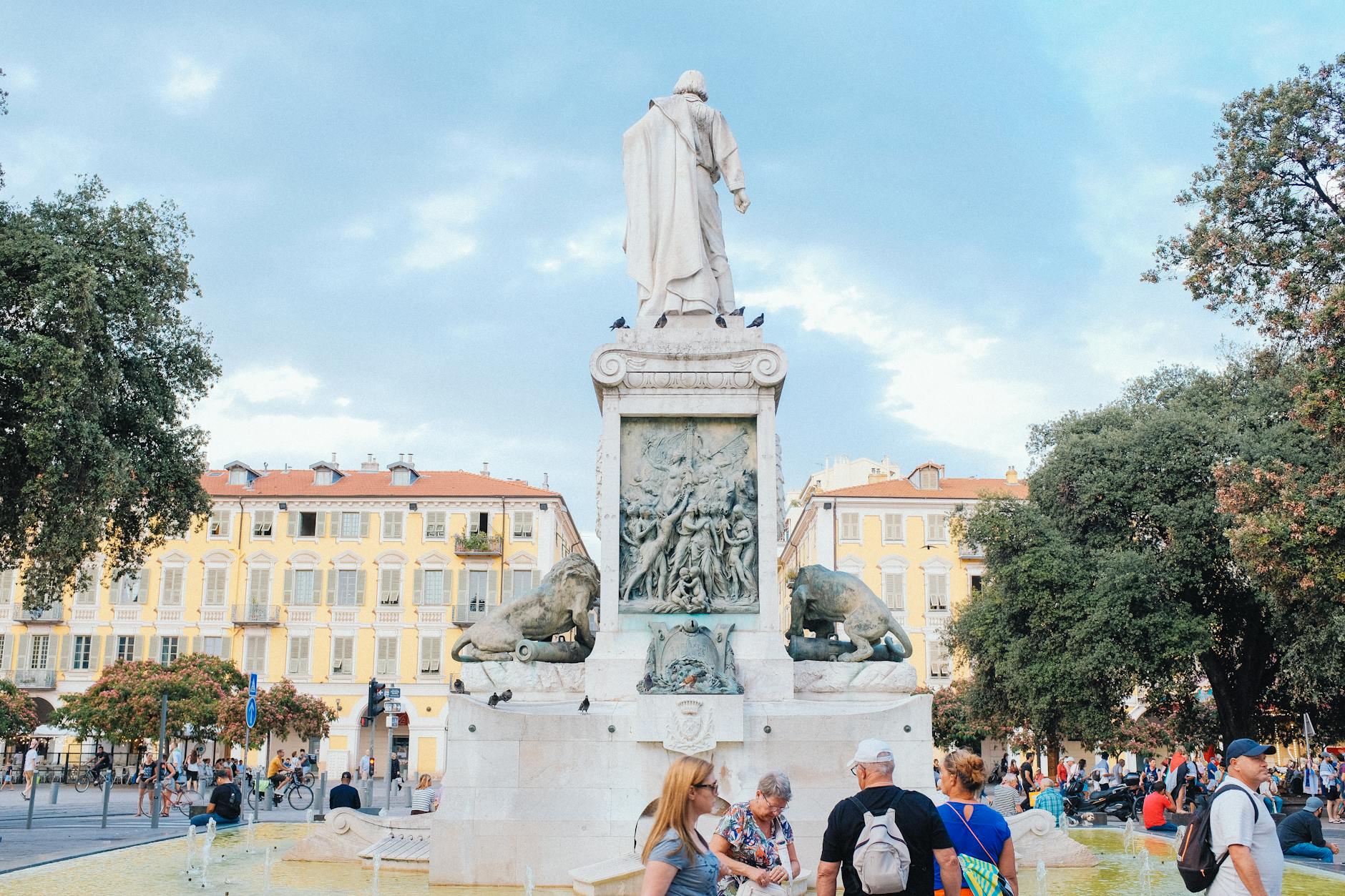 Historic square in Nice with a statue and people walking