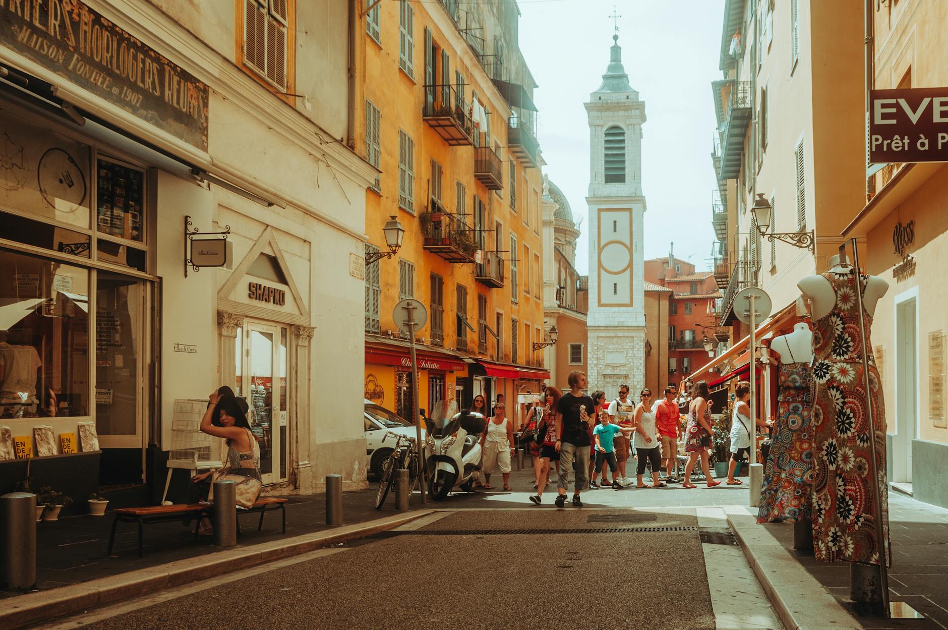 Busy street scene with shops and a church tower