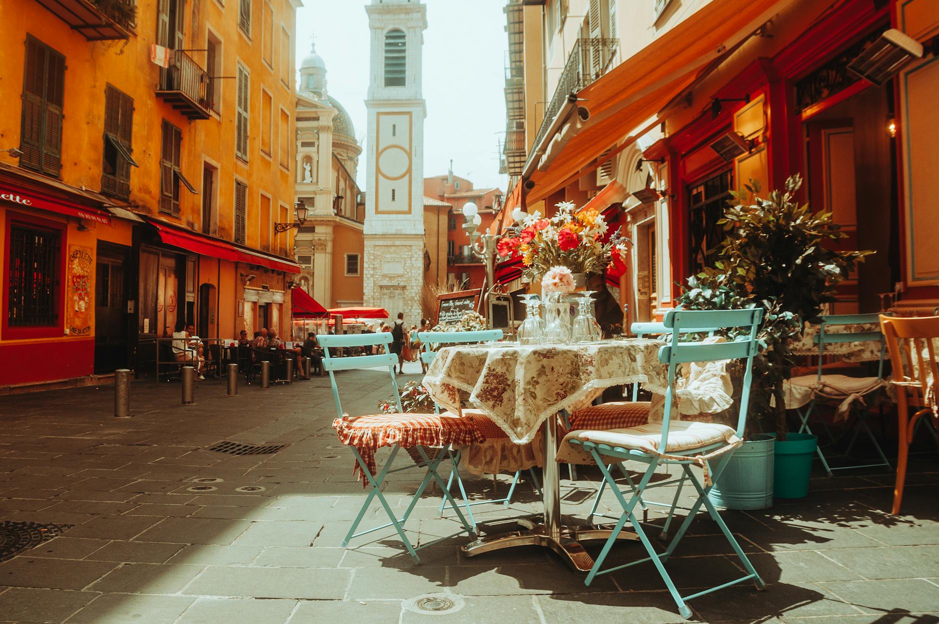 Colorful French cafe terrace with flowers and church tower