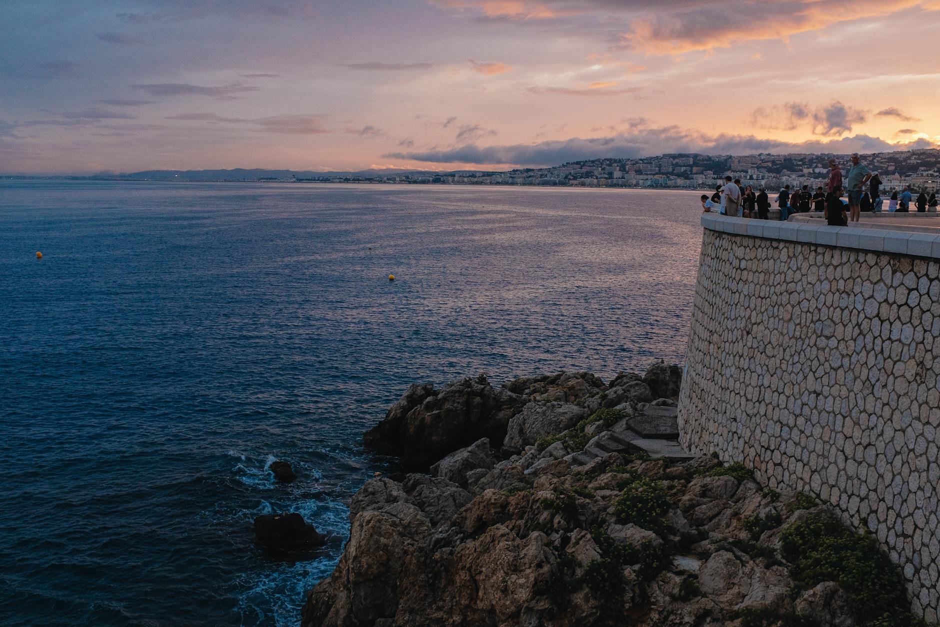 Sunset over a coastal promenade with people by the sea